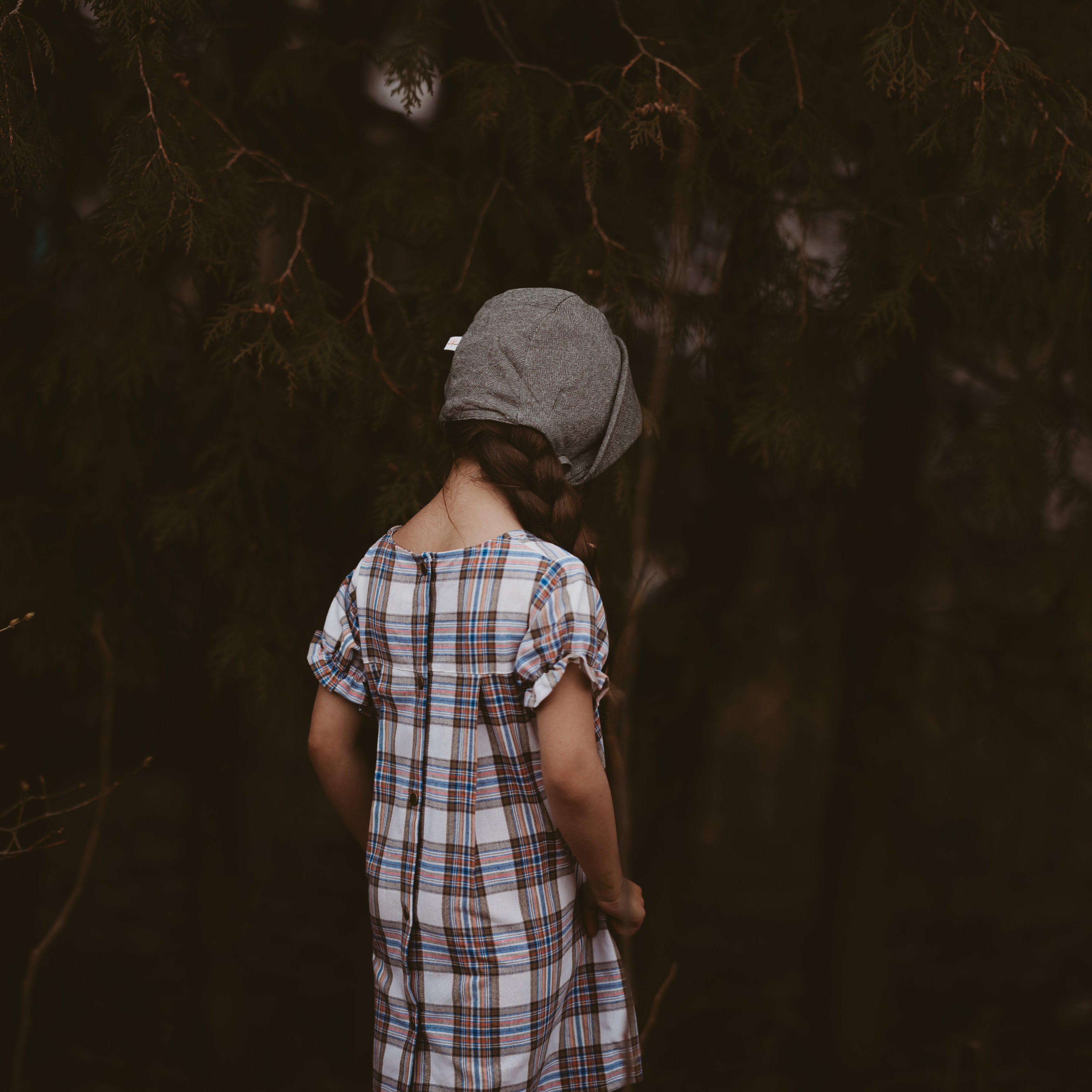 Girl in a plaid dress and green bonnet from the back