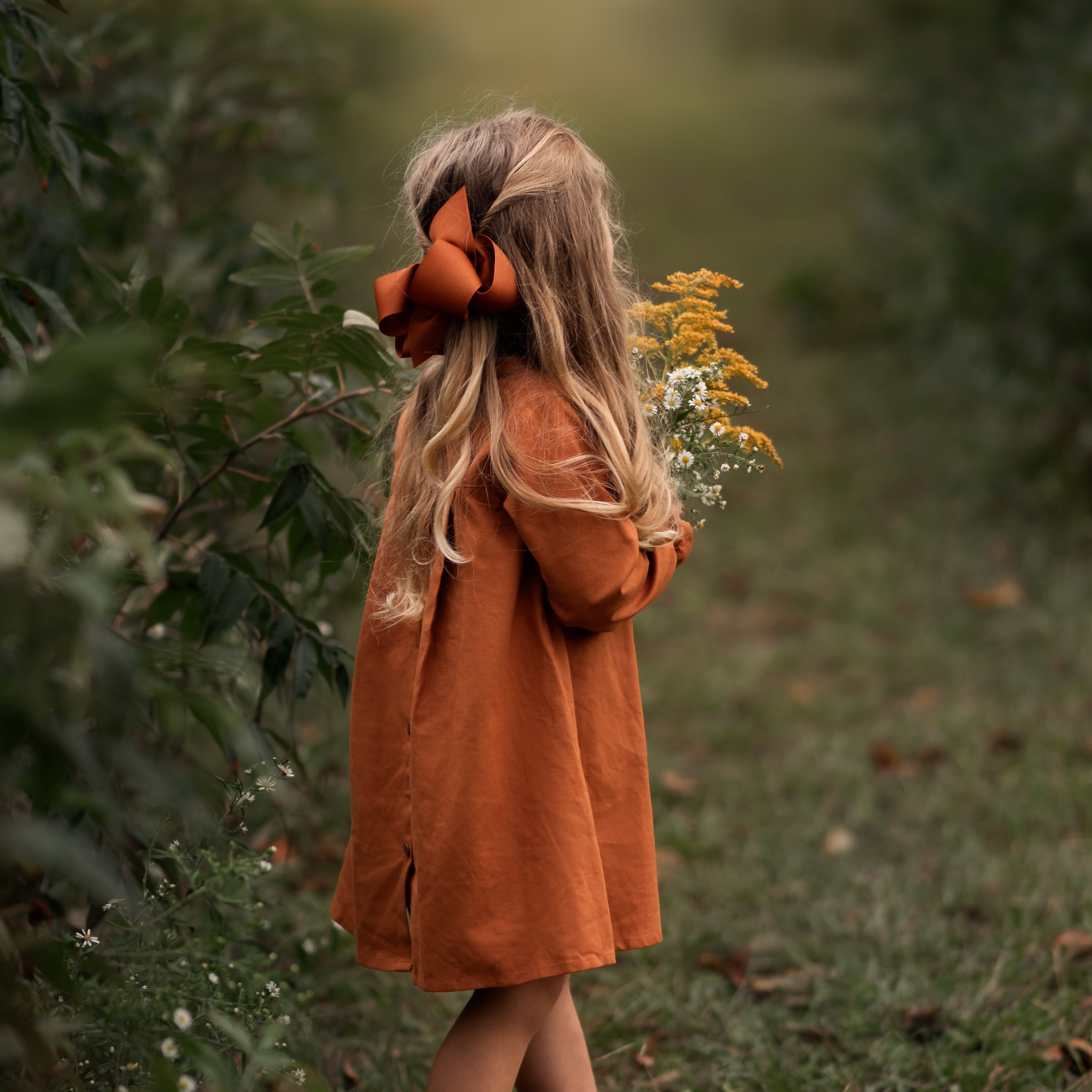 Model girl showcasing the back view with a playful pose - This photo captures the model in a fun pose, highlighting the dress’s playful ruffled sleeves and its stylish silhouette.