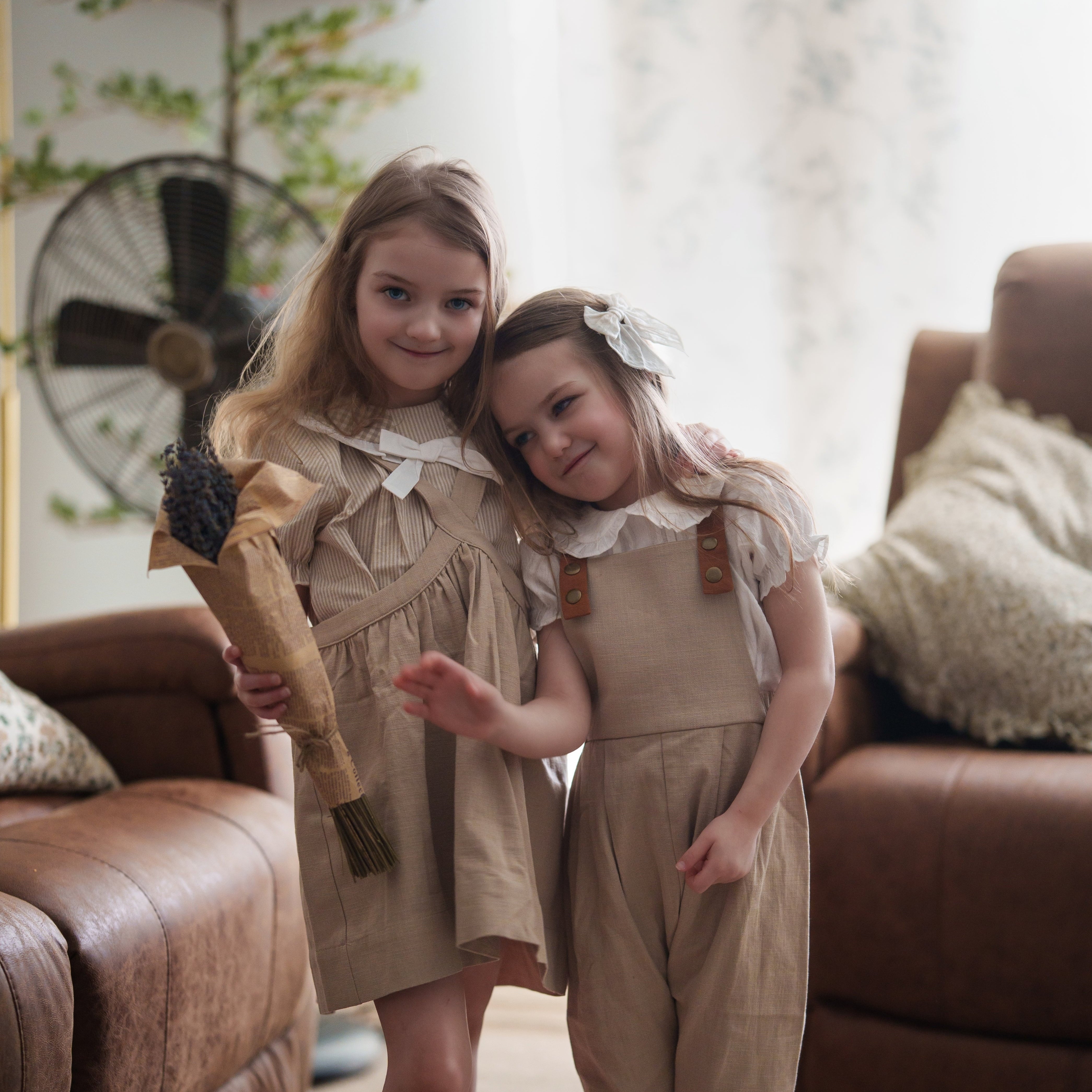 Two young girls in matching outfits standing in a living room.