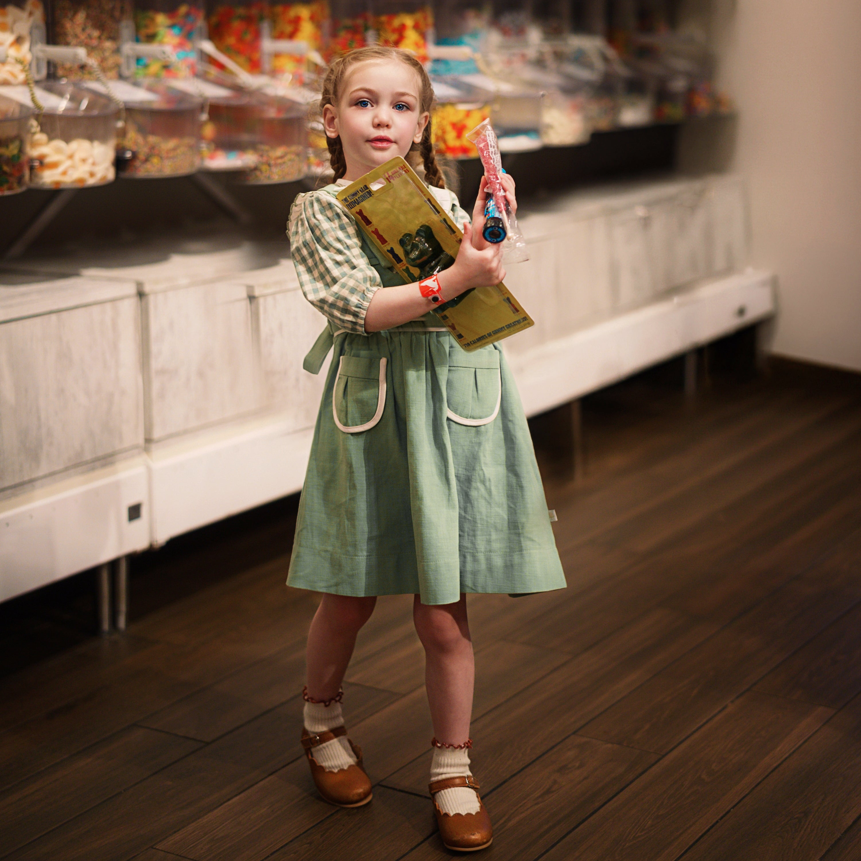 Young girl in a candy store holding a book and lollipop.