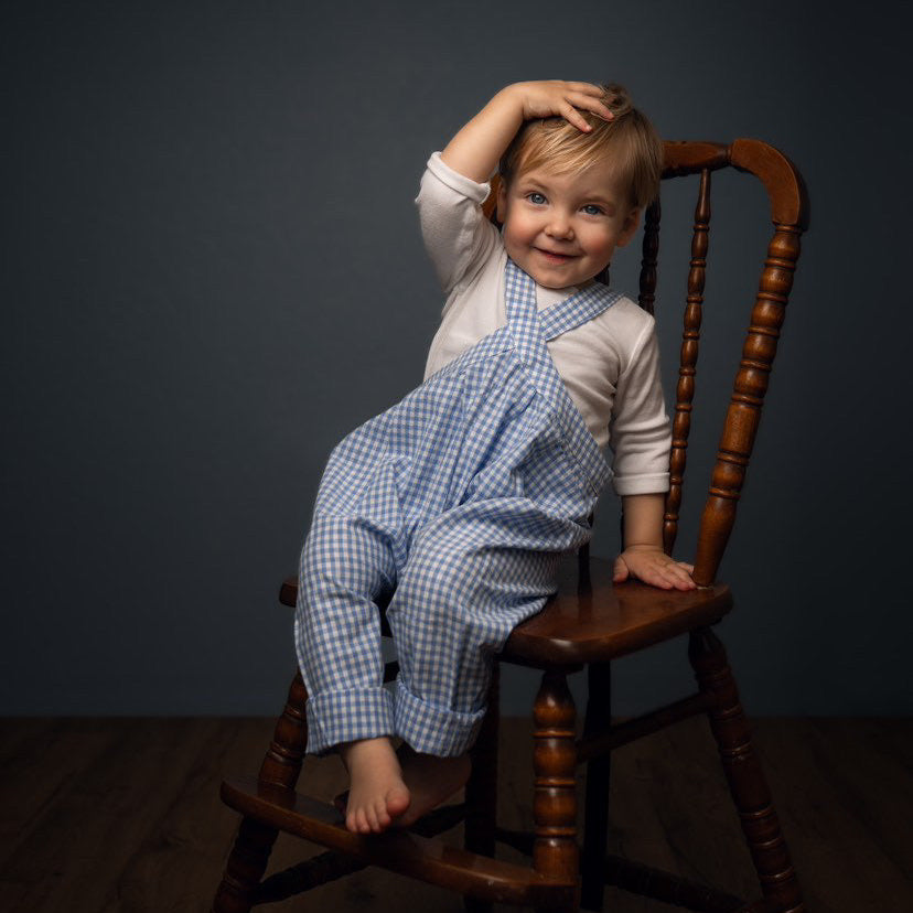 blue gingham overalls on a boy sitting on a chair