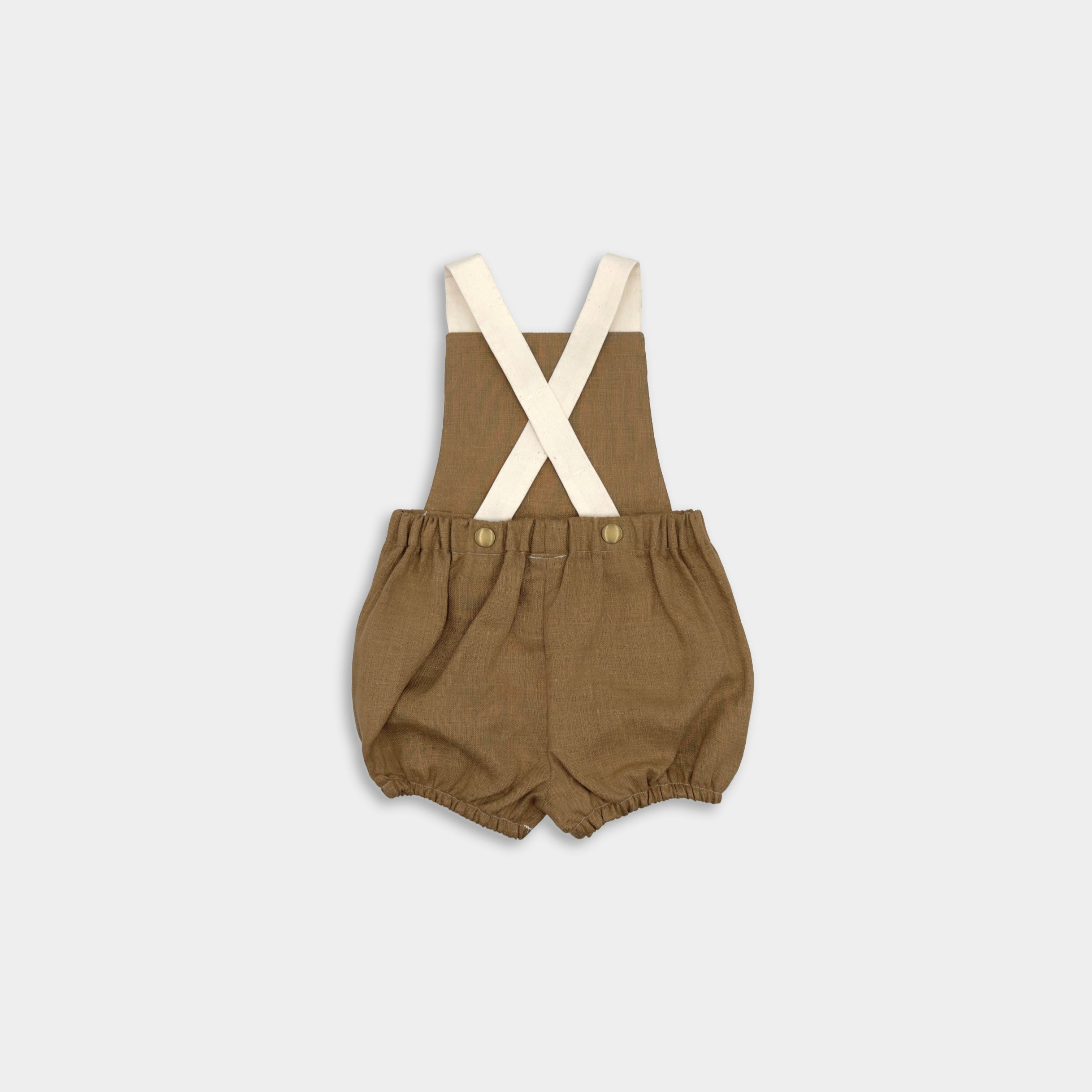 Back view of a handmade linen bubble romper in Beachwood, featuring adjustable contrasting straps in cream for a customizable fit and elasticized legs for easy movement during summer play. A gender-neutral design that combines timeless style with comfort, perfect for any occasion.