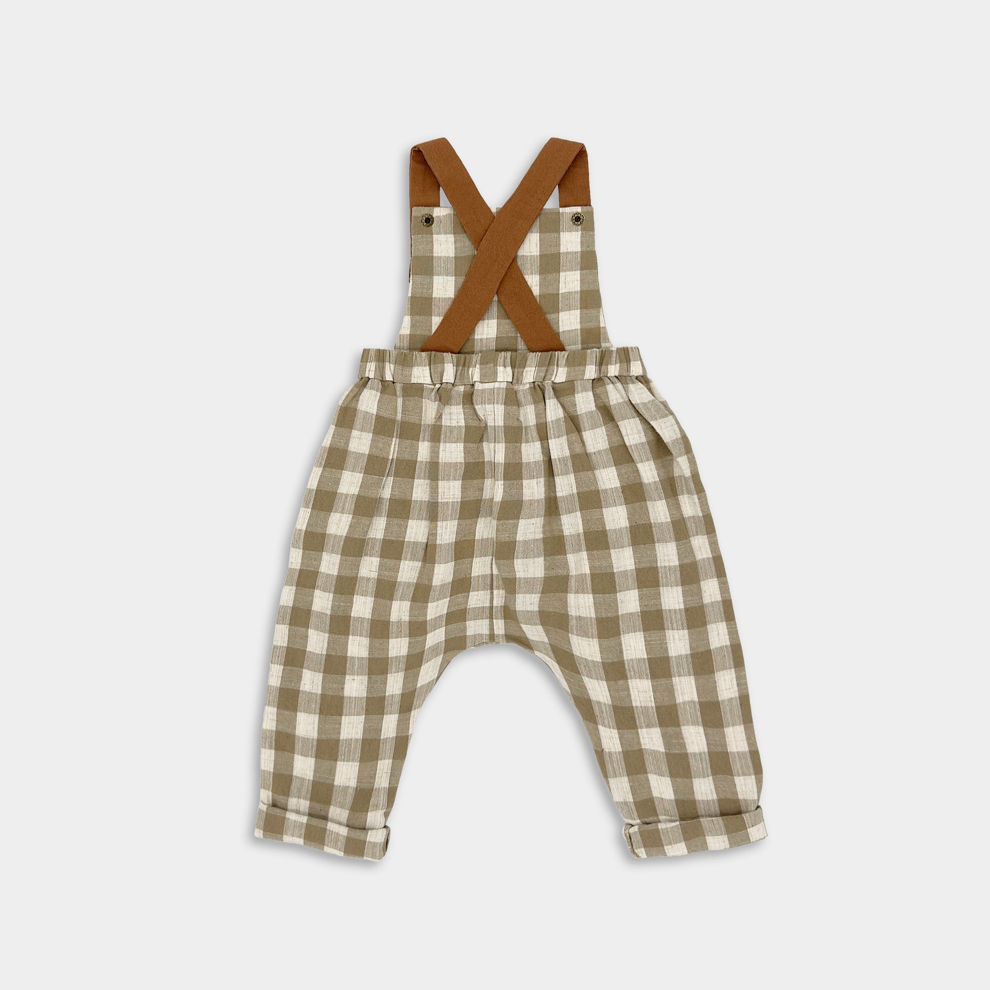 Back view of Beige Gingham linen long overalls for children, featuring gender-neutral design, breathable fabric for all-day comfort, stylish pleats for elegance, durable contrasting leather-looking straps, adjustable straps for a perfect fit, and unfoldable leg cuffs that allow for growth.