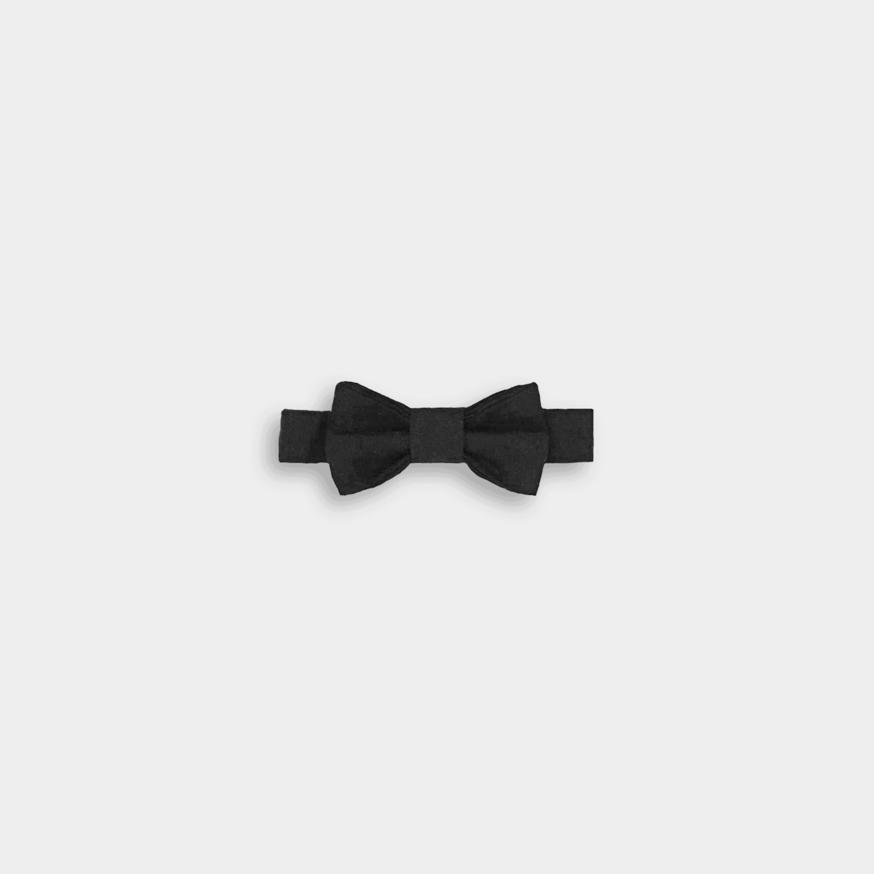 A black linen classic bow tie, featuring a timeless design, versatile for various outfits, available in two sizes for wearing over a shirt or on its own, and perfectly complementing bestselling suspender shorts and overalls.