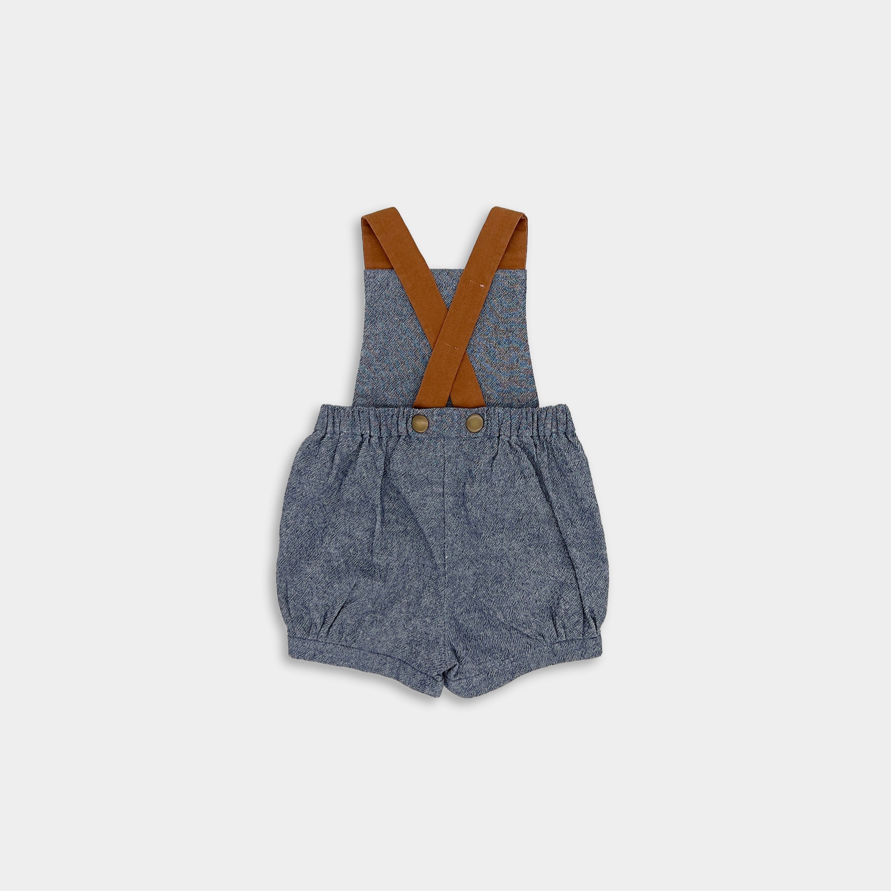 Back view of chambray blue linen short overalls displayed on its own, highlighting the elegant design and sustainable materials used in making high-quality children’s clothing.