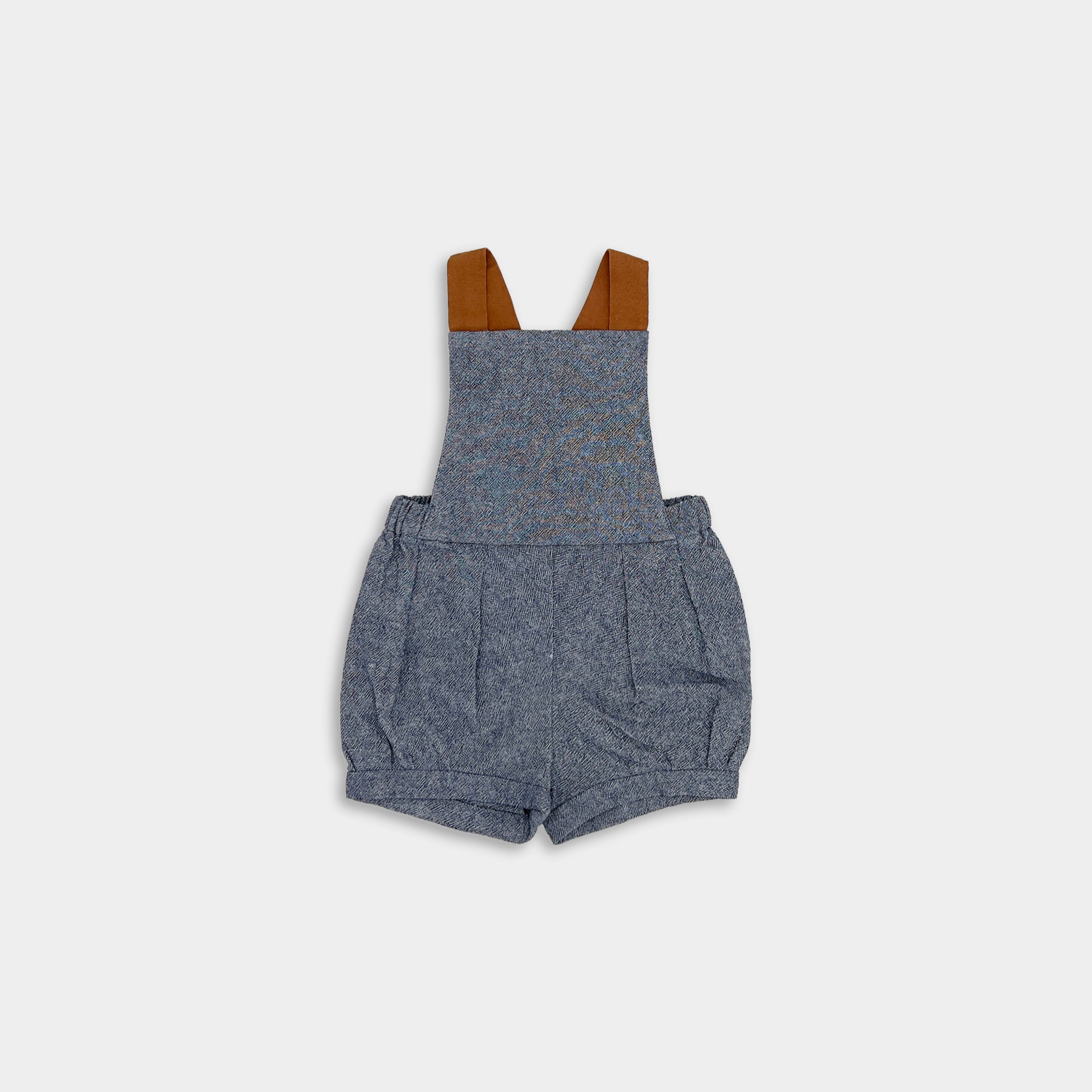 Front view of stylish chambray blue linen short overalls, showcasing elegant pleats and cuffs, emphasizing high-quality craftsmanship for children’s wear.