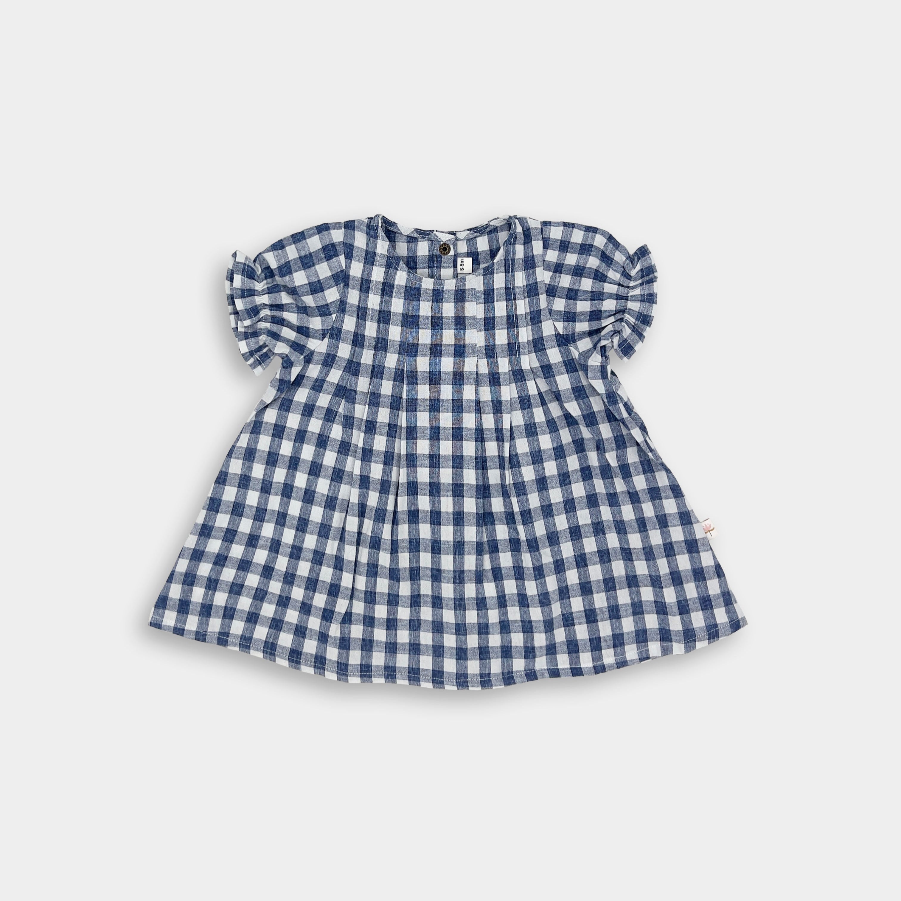 A full view of a Blue Gingham linen dress, showcasing its beautiful design with a pin-tucked front and a yoke featuring two pleats at the back. The dress has delicate ruffles at the short sleeve hem and an A-line shape, perfect for warm summer days. Pre-washed to ensure it retains its shape and minimizes shrinking, this dress embodies a charming and practical style for little girls.