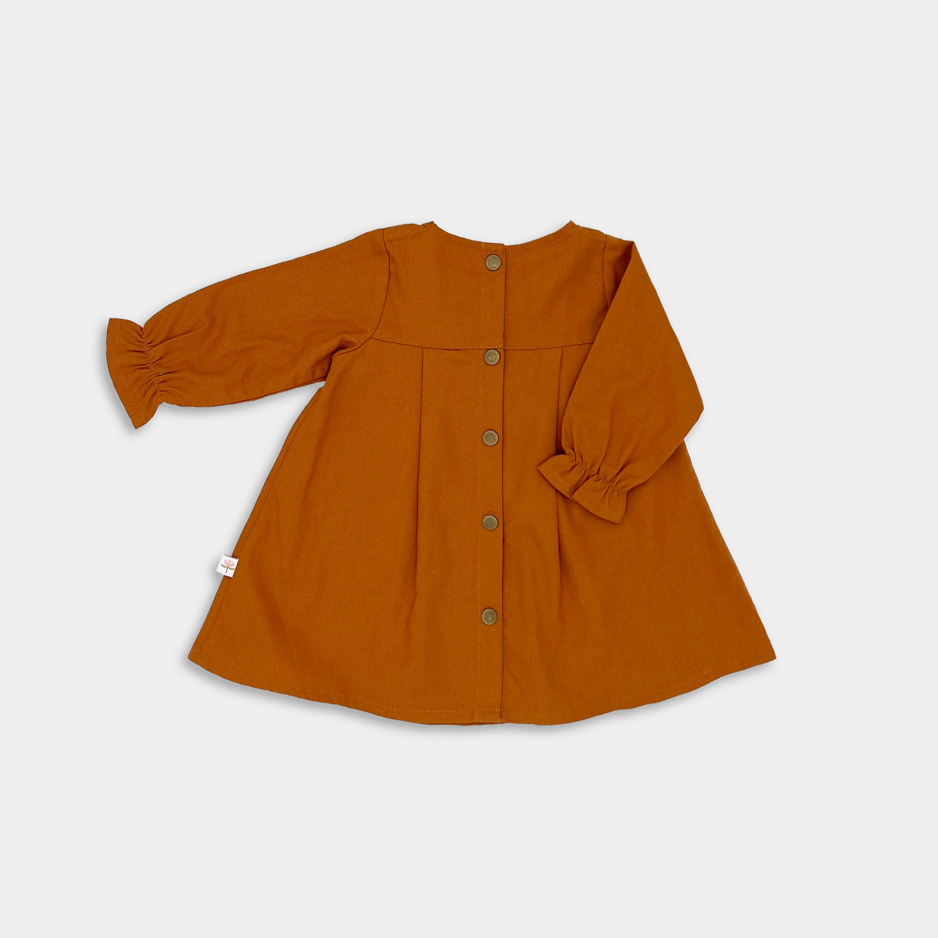 Back view of the Burnt Orange Linen Dress alone - Capturing the back of the dress, this image emphasizes the pleated back yoke and the ruffled details at the sleeves, showcasing the thoughtful design.