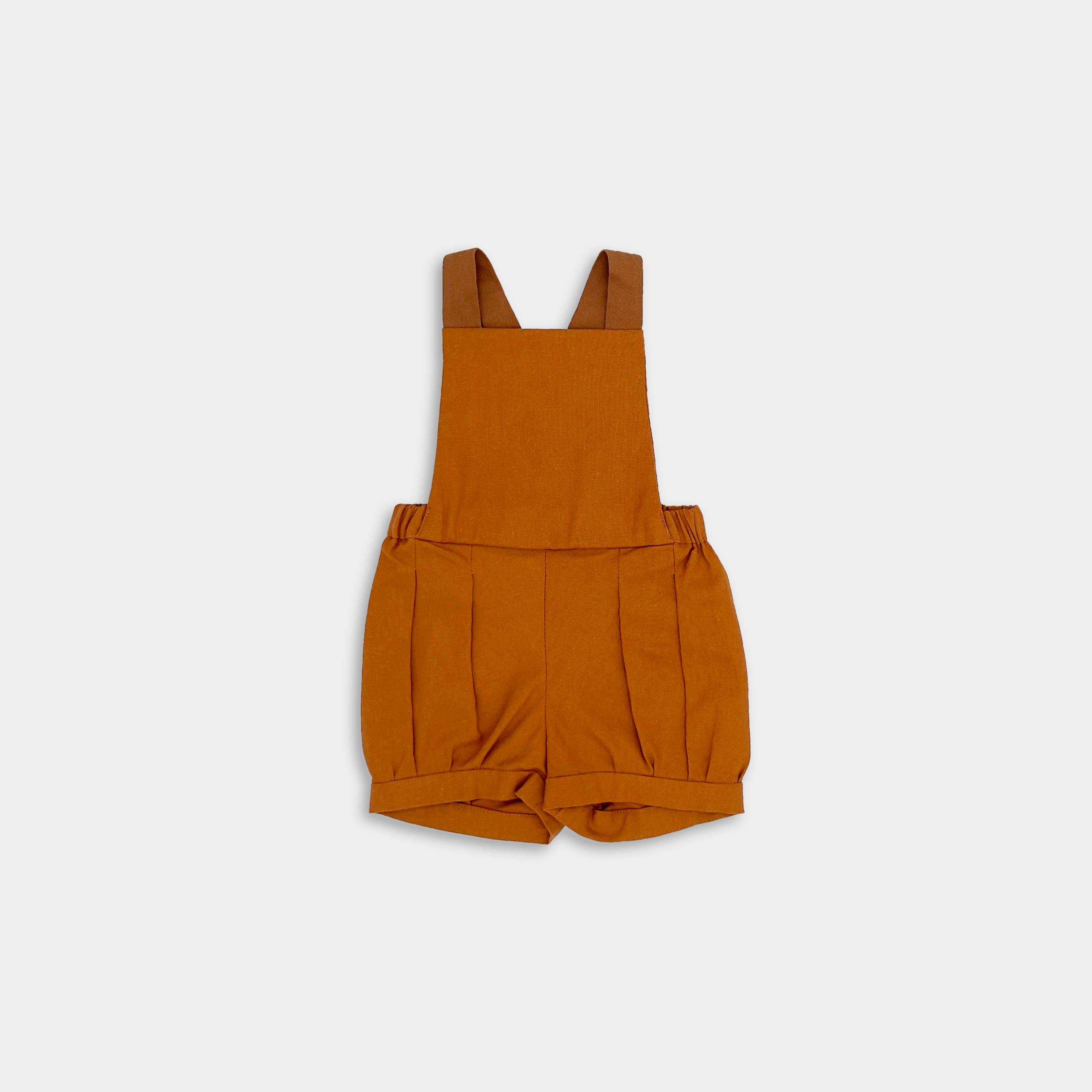 Photo of the Burnt Orange Short Overalls alone - This image showcases the stylish design of the shortalls, highlighting their elegant pleats, cuffs, and leather-looking straps.