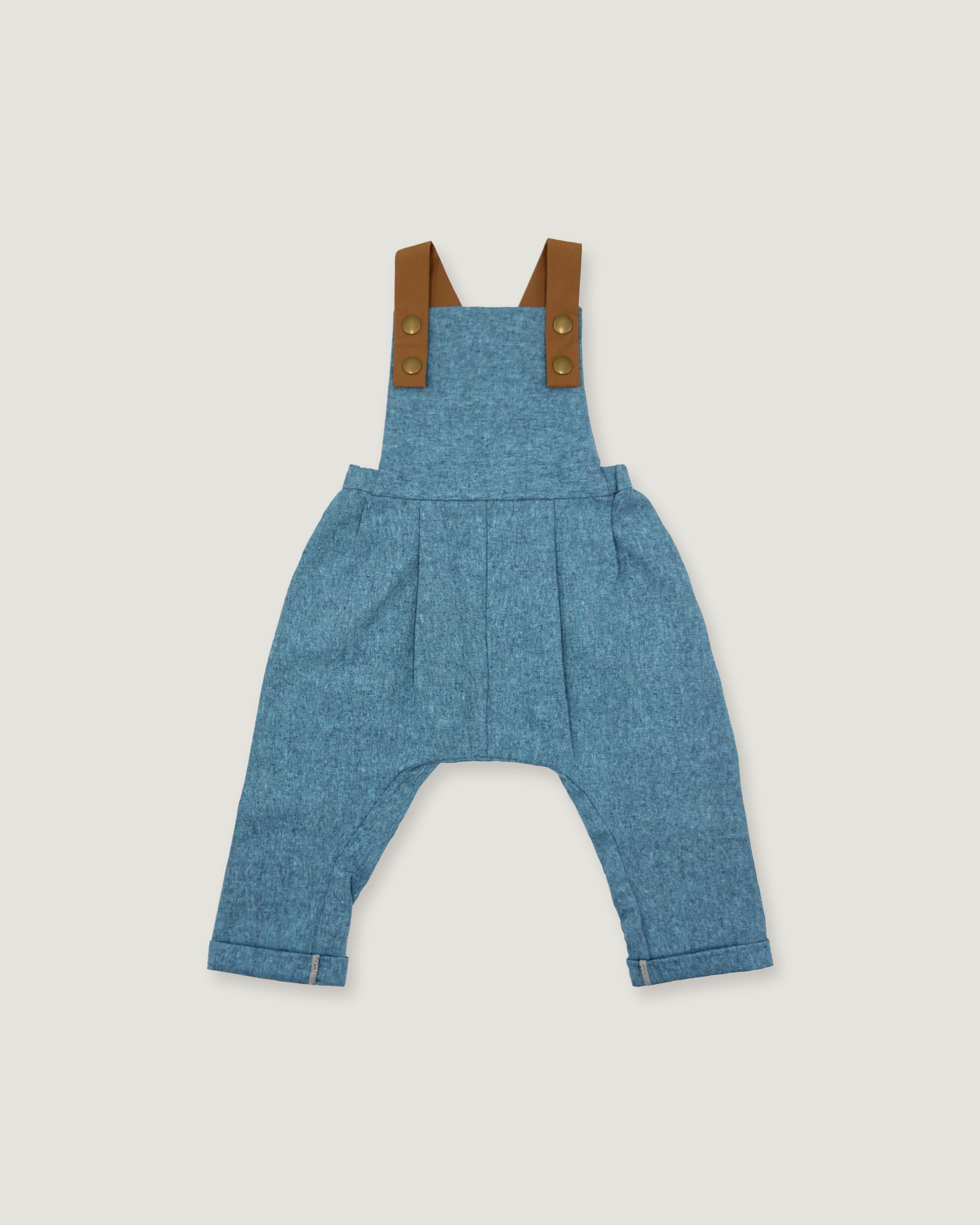 A pair of baby blue denim overall-style pants with brown shoulder straps and brass-tone buttons, shown flat against a light gray background.