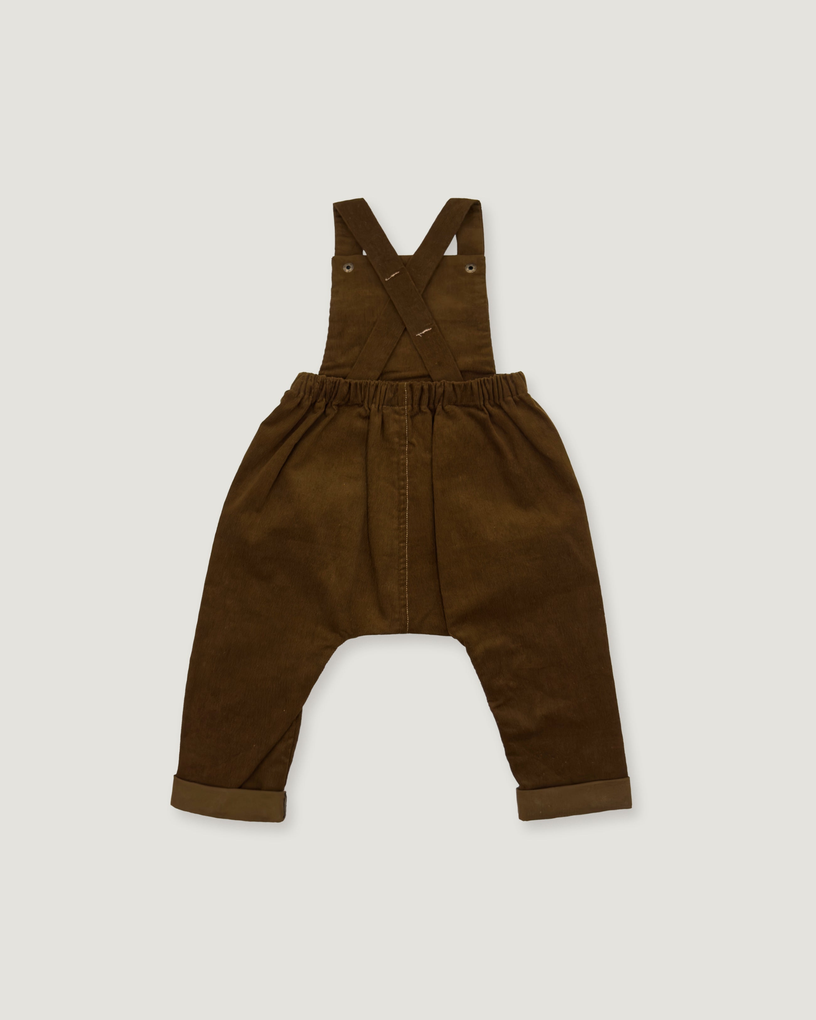 A pair of dark brown corduroy baby overalls with adjustable shoulder straps and a wide elastic waistband, laid flat on a light gray background.