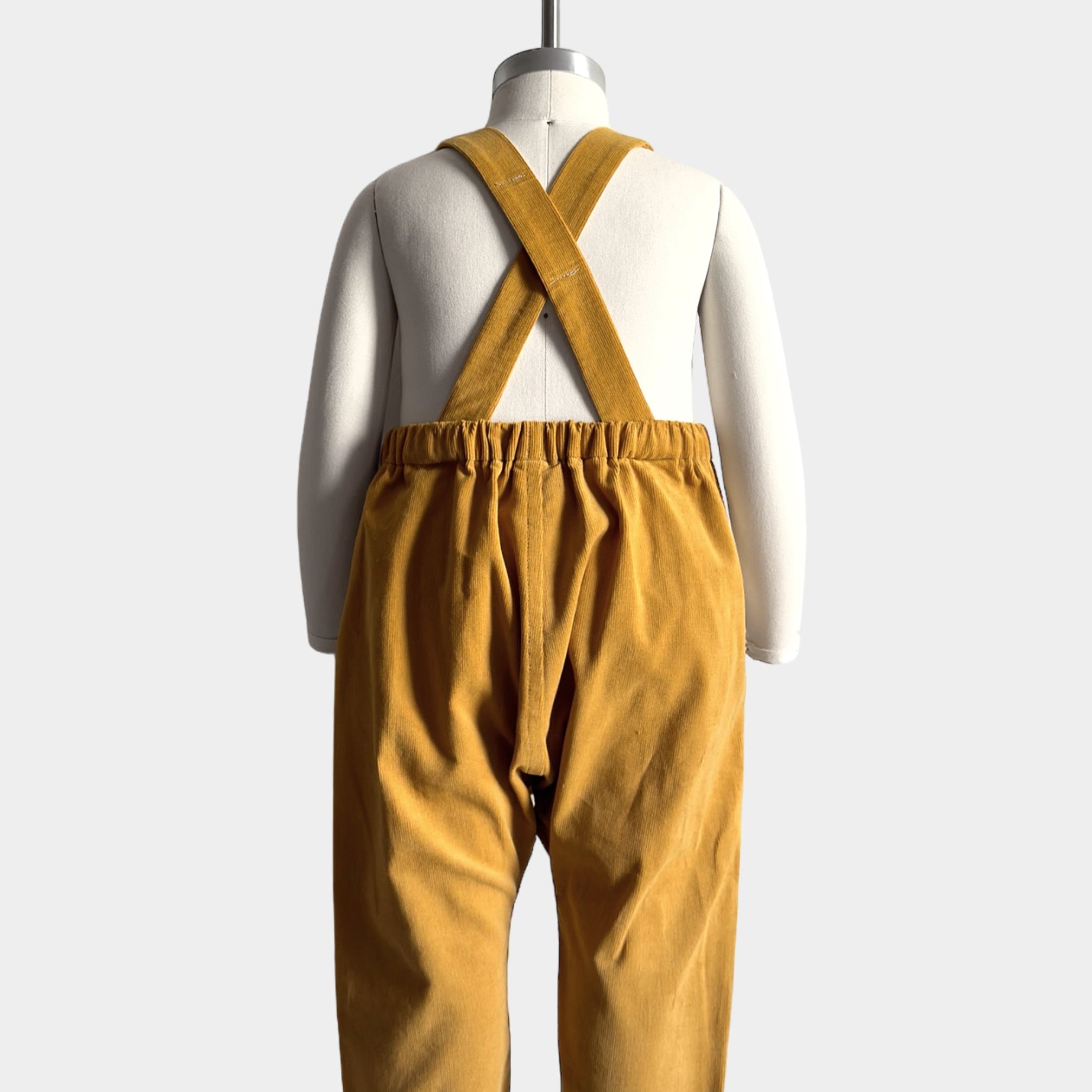 Back view of the mannequin in the overalls, showcasing the adjustable straps and overall construction. Adjustable straps stay up thanks to the strategically placed label. Elasticized back for comfort and best fit.