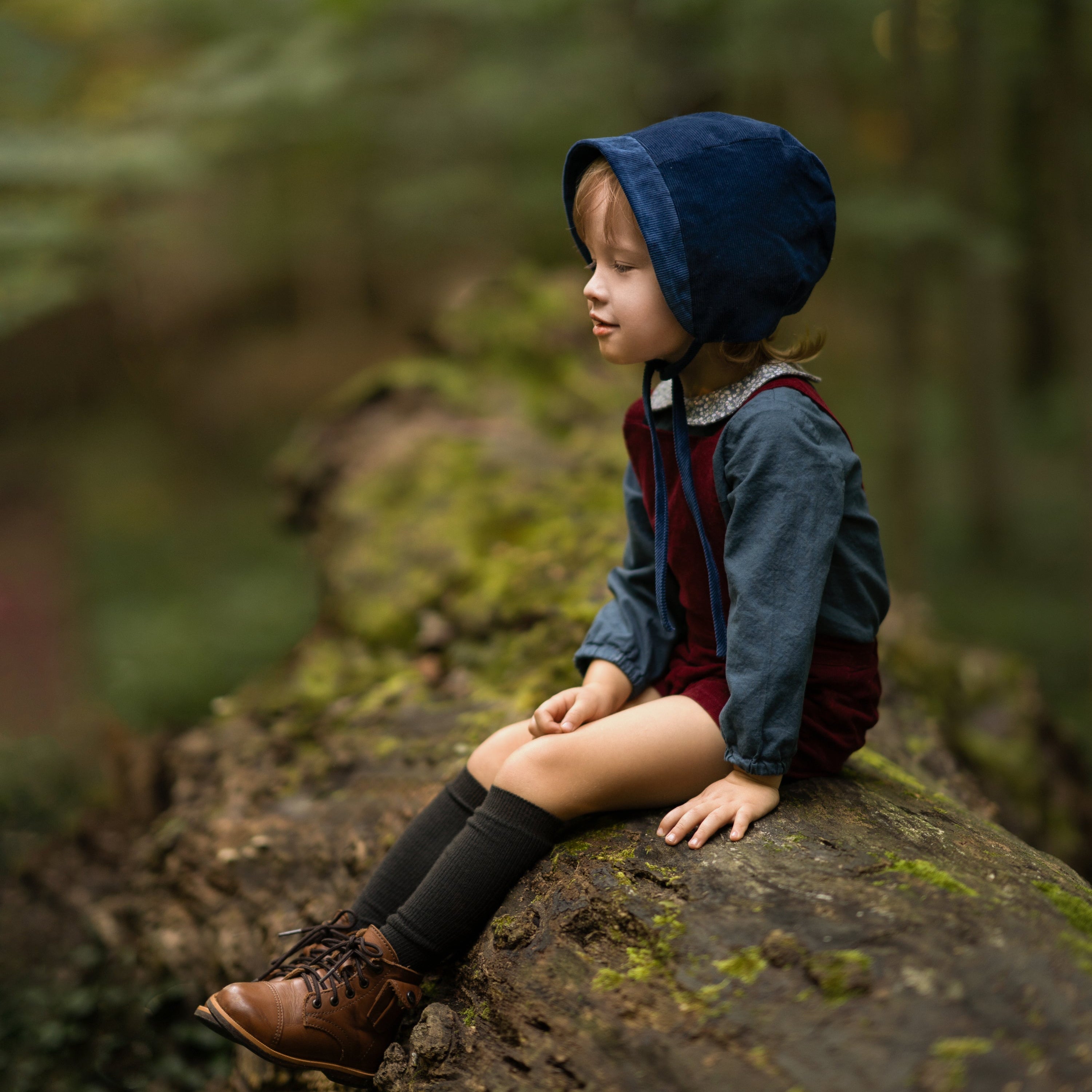 Boy in a blue bonnet sitting on a rock