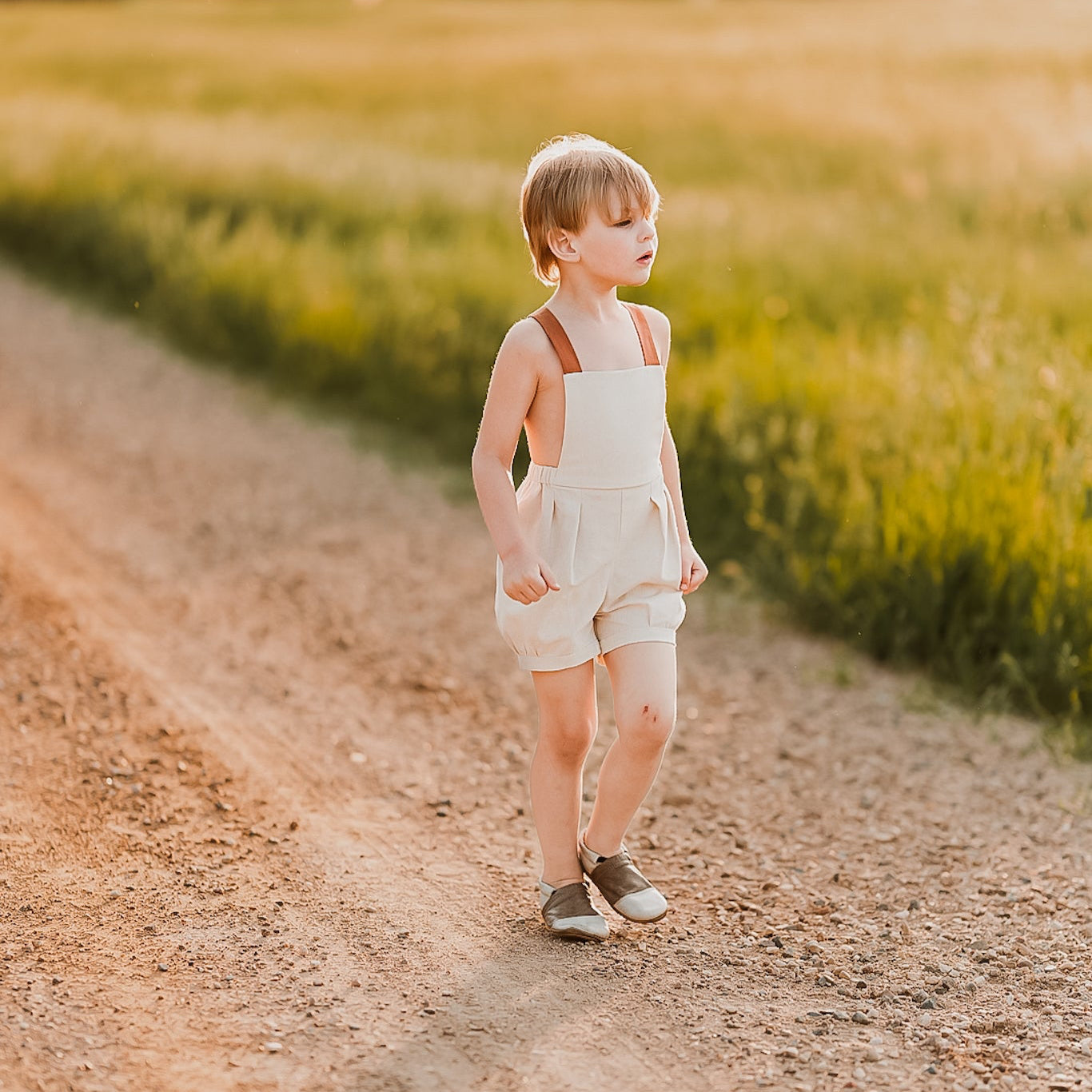 Boy walking on a dirt road in natural overalls