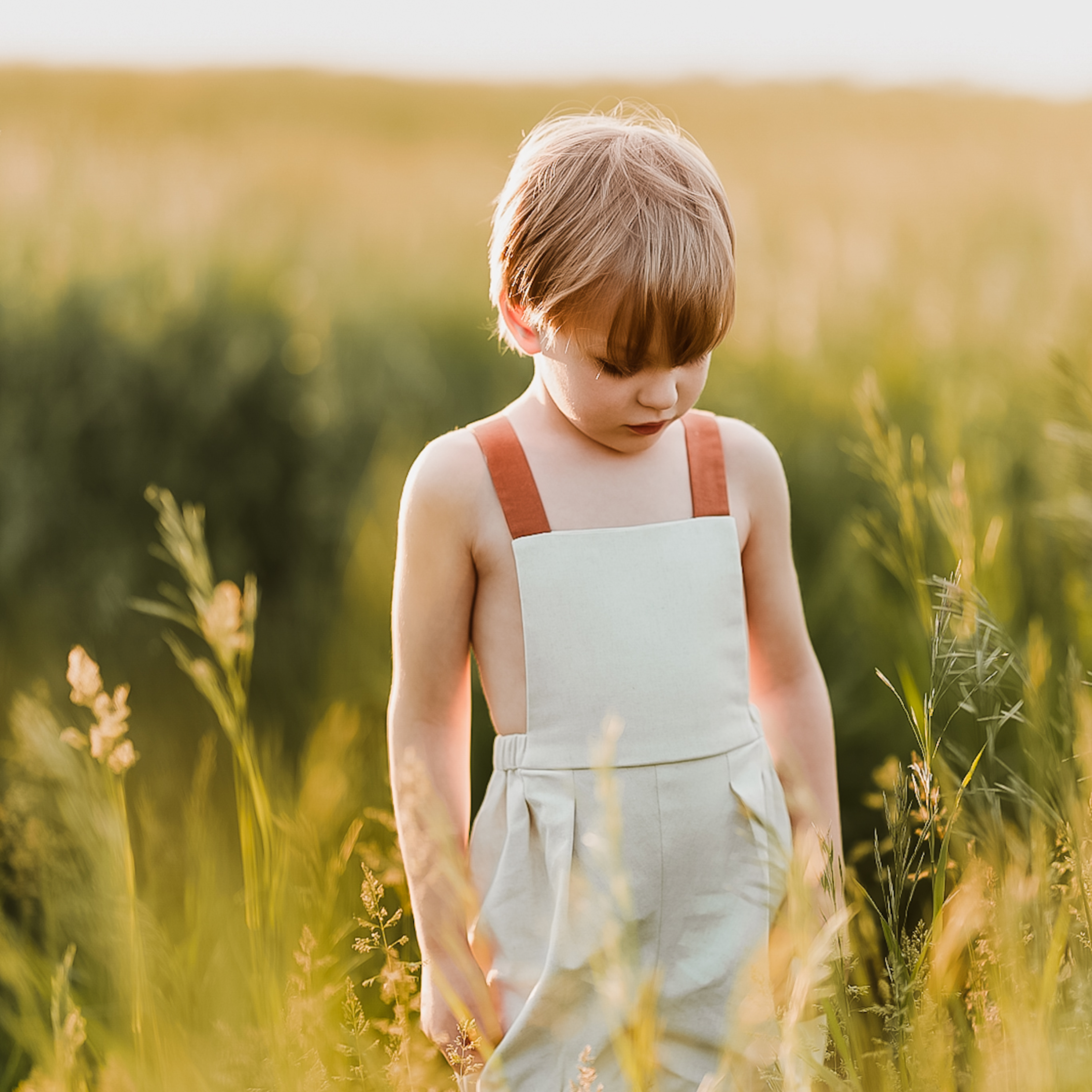 Boy in natural overalls in a yellow field