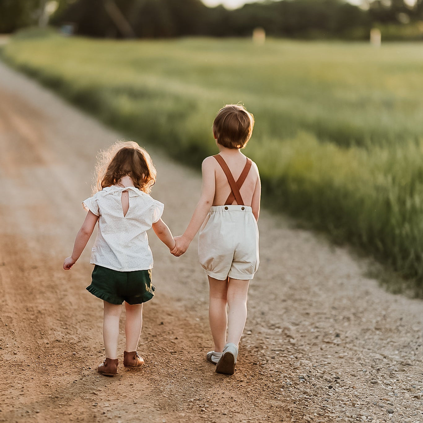 Boy and girl holding hands walking on a dirt road