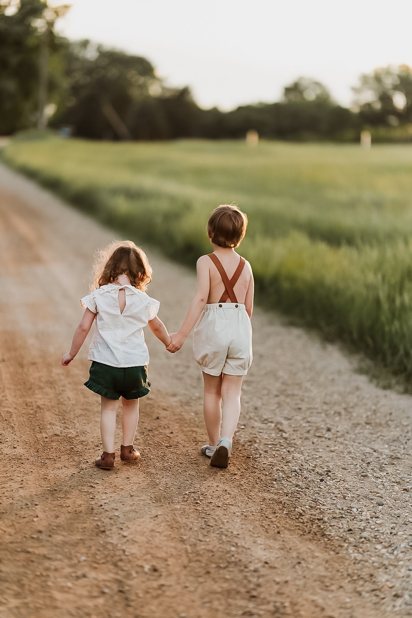 Boy and girl holding hands walking on a dirt road
