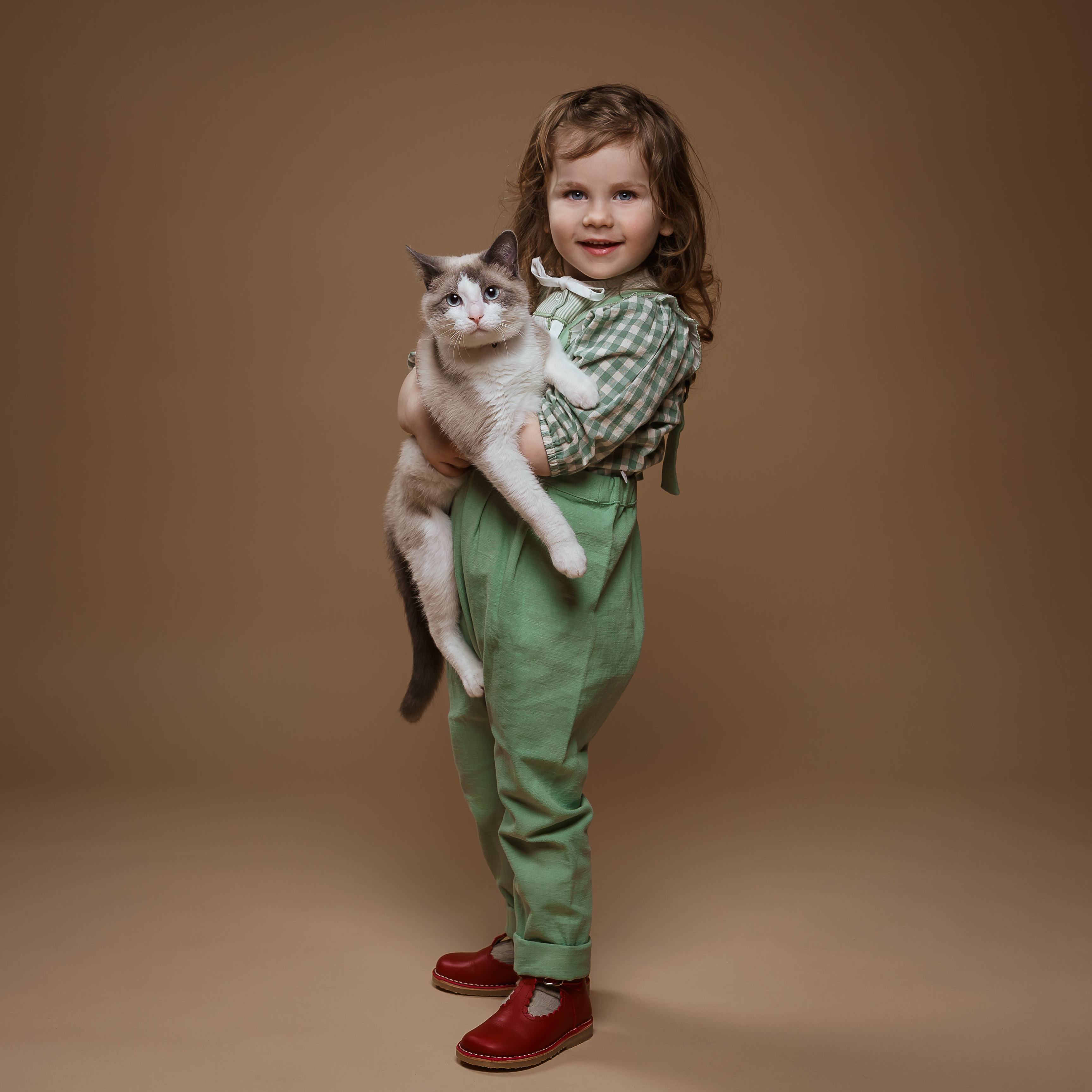 Child holding a cat against a brown background