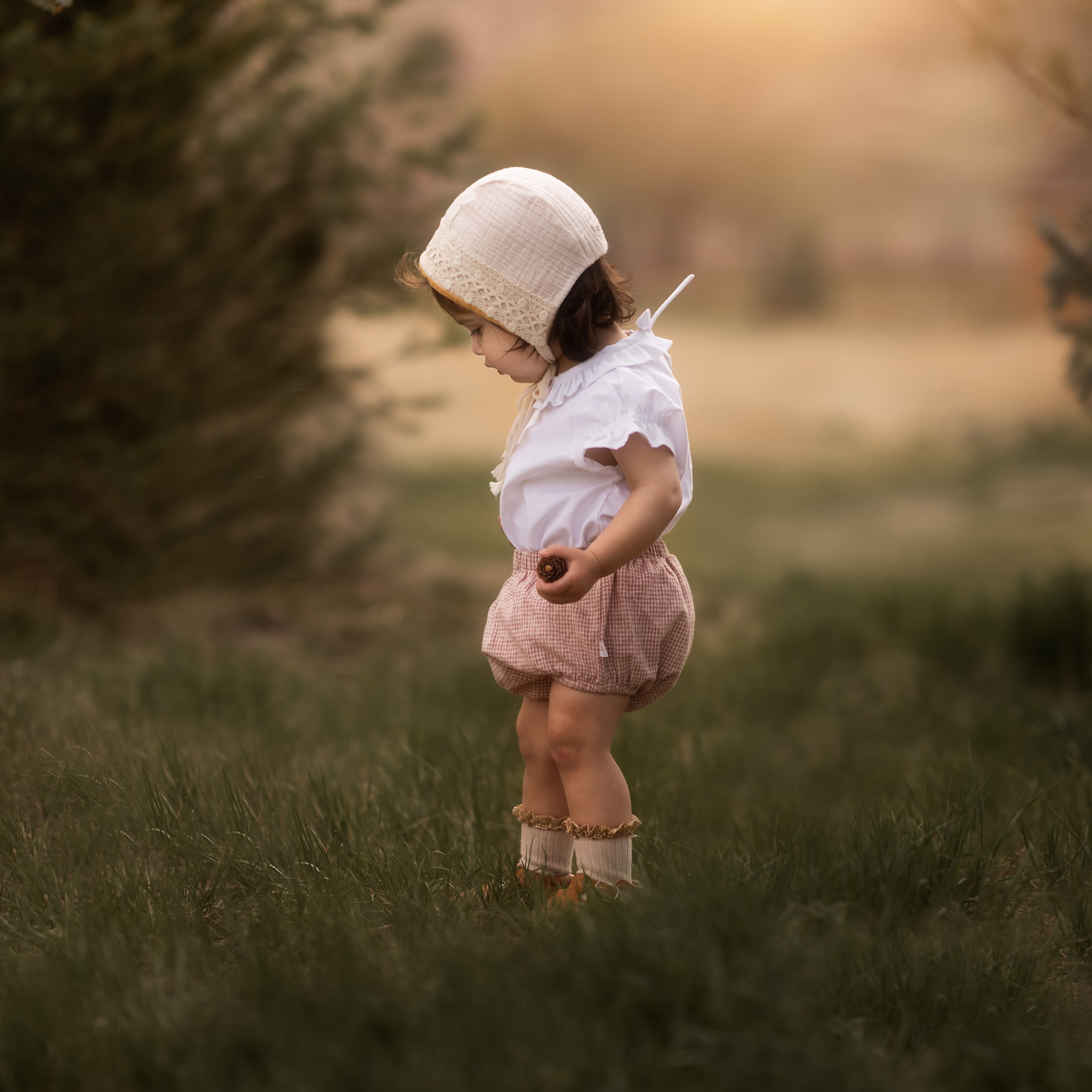 Baby in a bonnet and bloomers in a blurred field