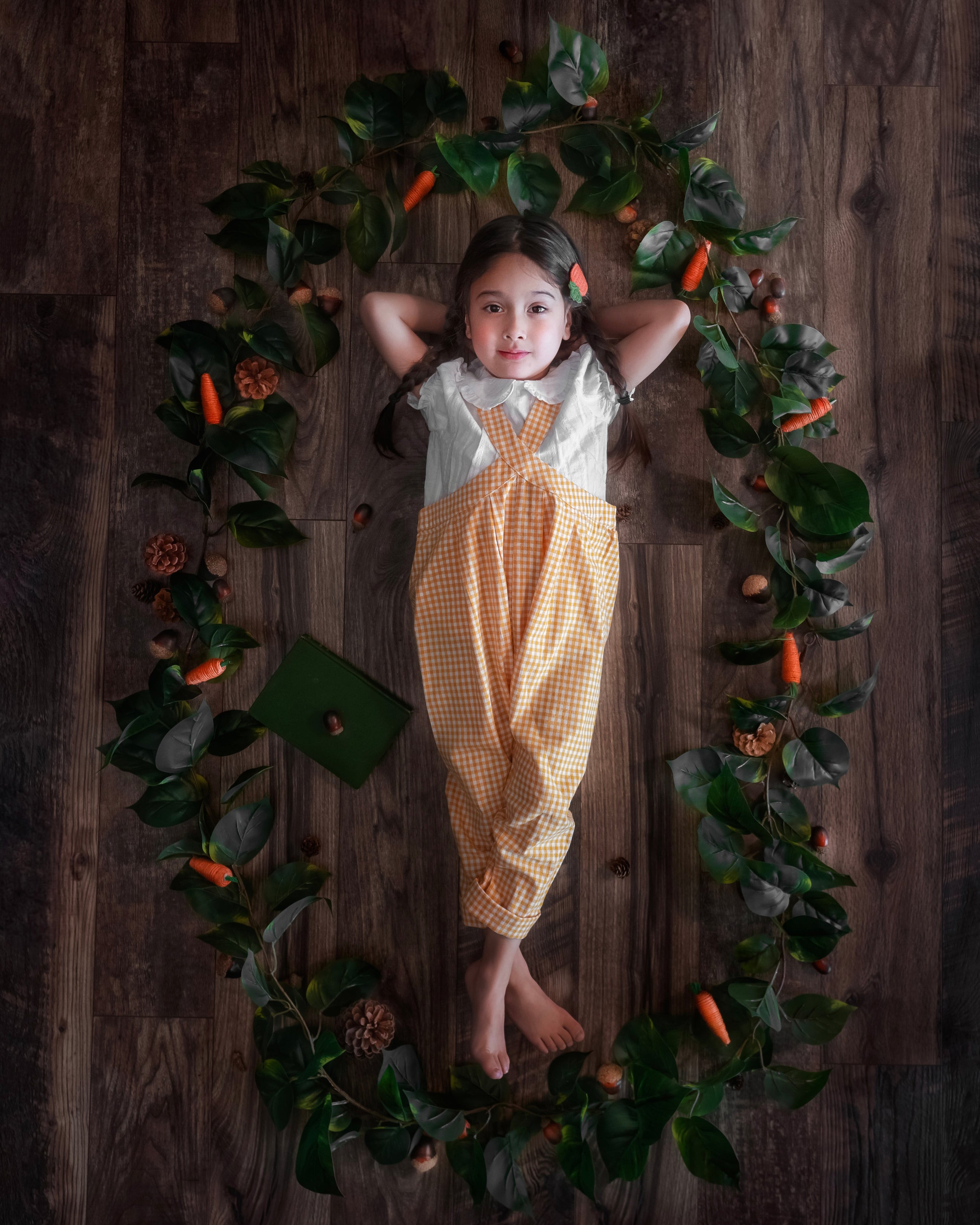Child in a checkered outfit lying on a wooden floor with decorative elements