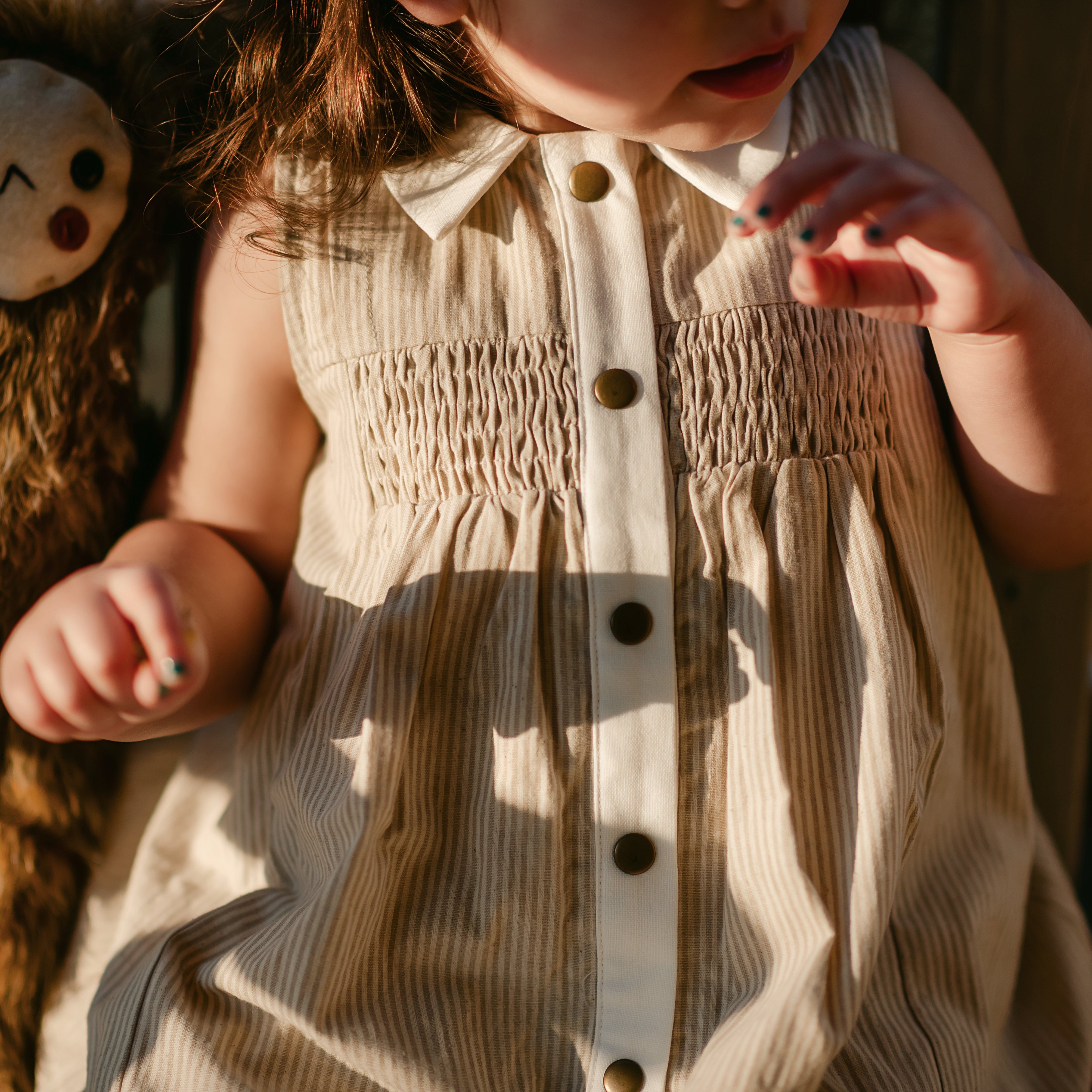 girl in a beige striped dress in the sun