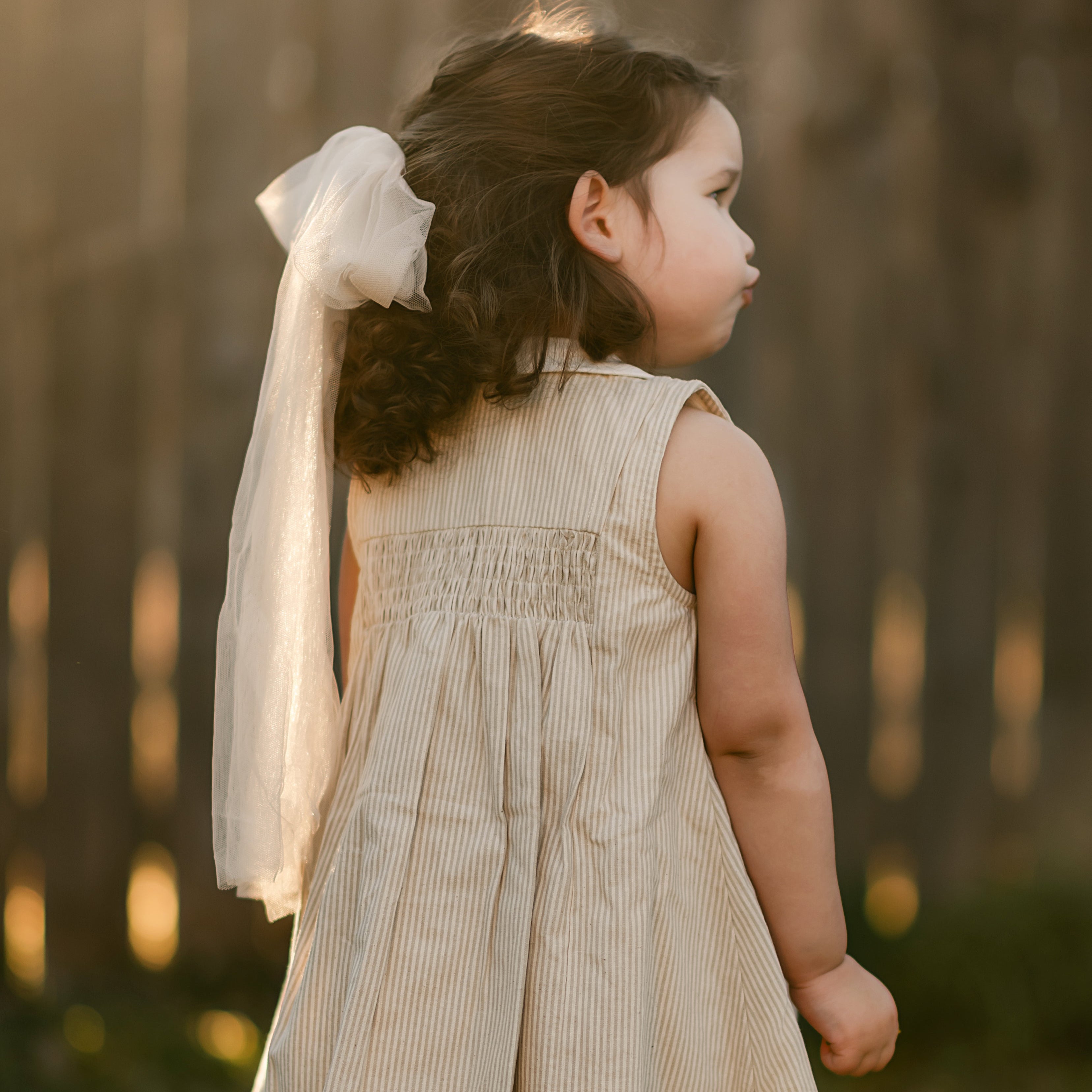 girl in a beige striped dress from the back