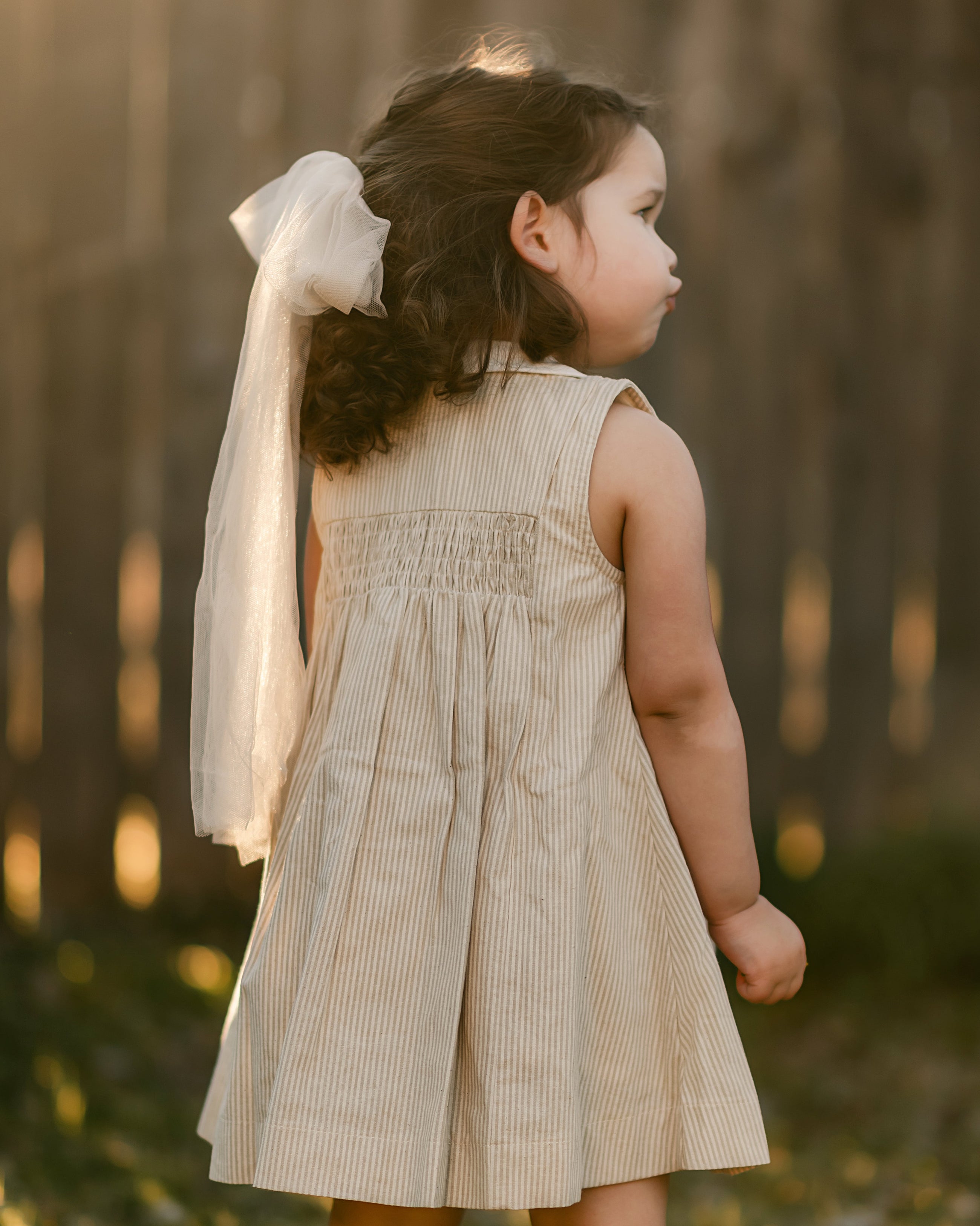 girl in a beige striped dress from the back