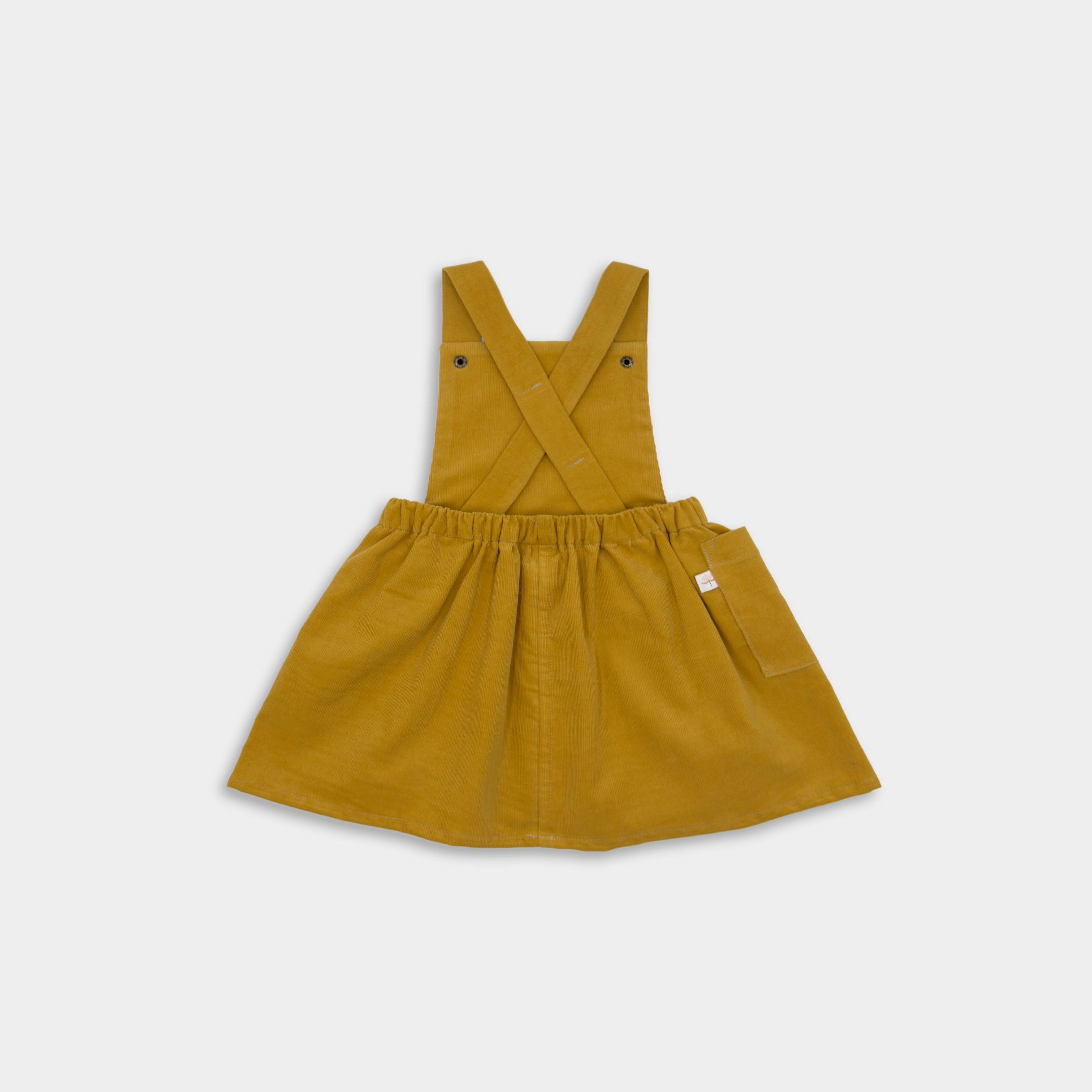 Back view of the Mustard Pinafore laying flat, highlighting its adjustable straps and classic design, perfect for easy wear and timeless style.
