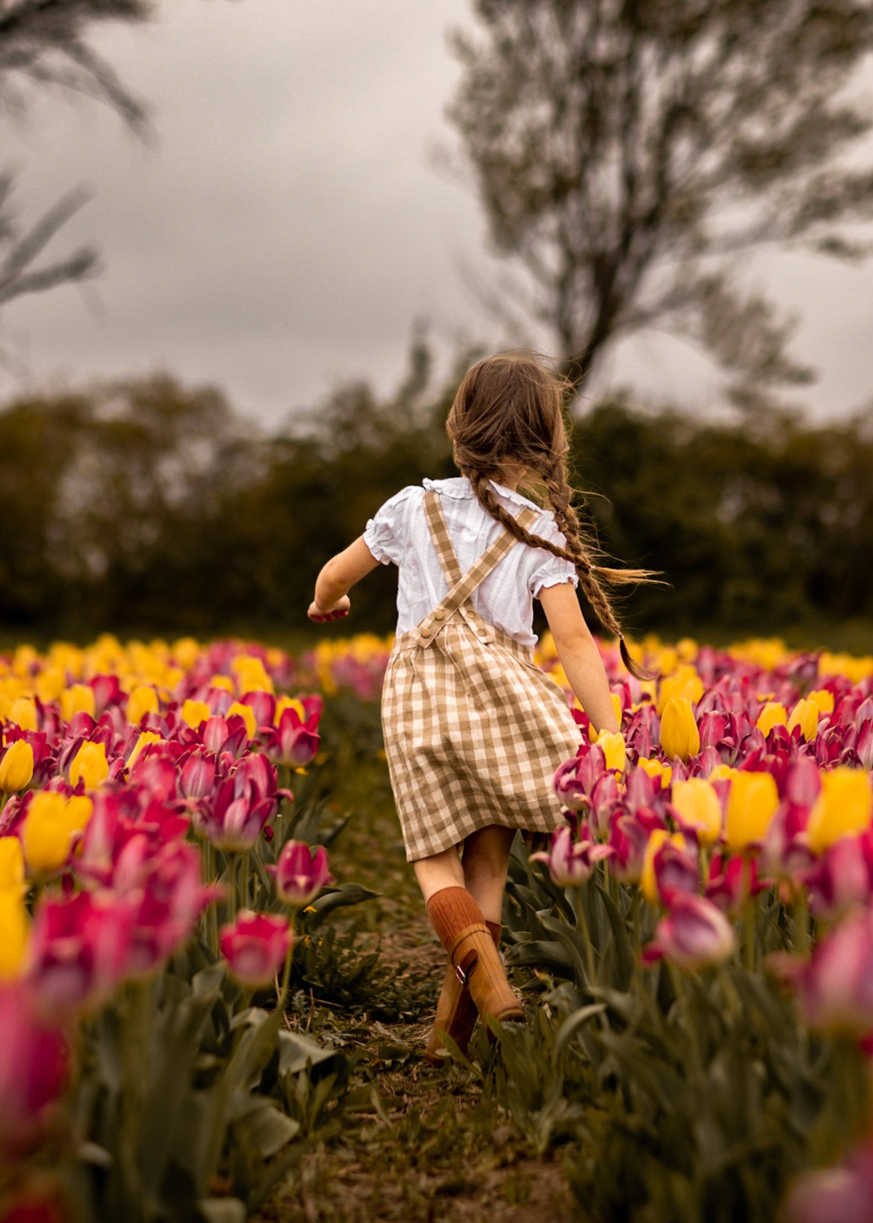 Girl running through a field of colorful tulips with a blurred background