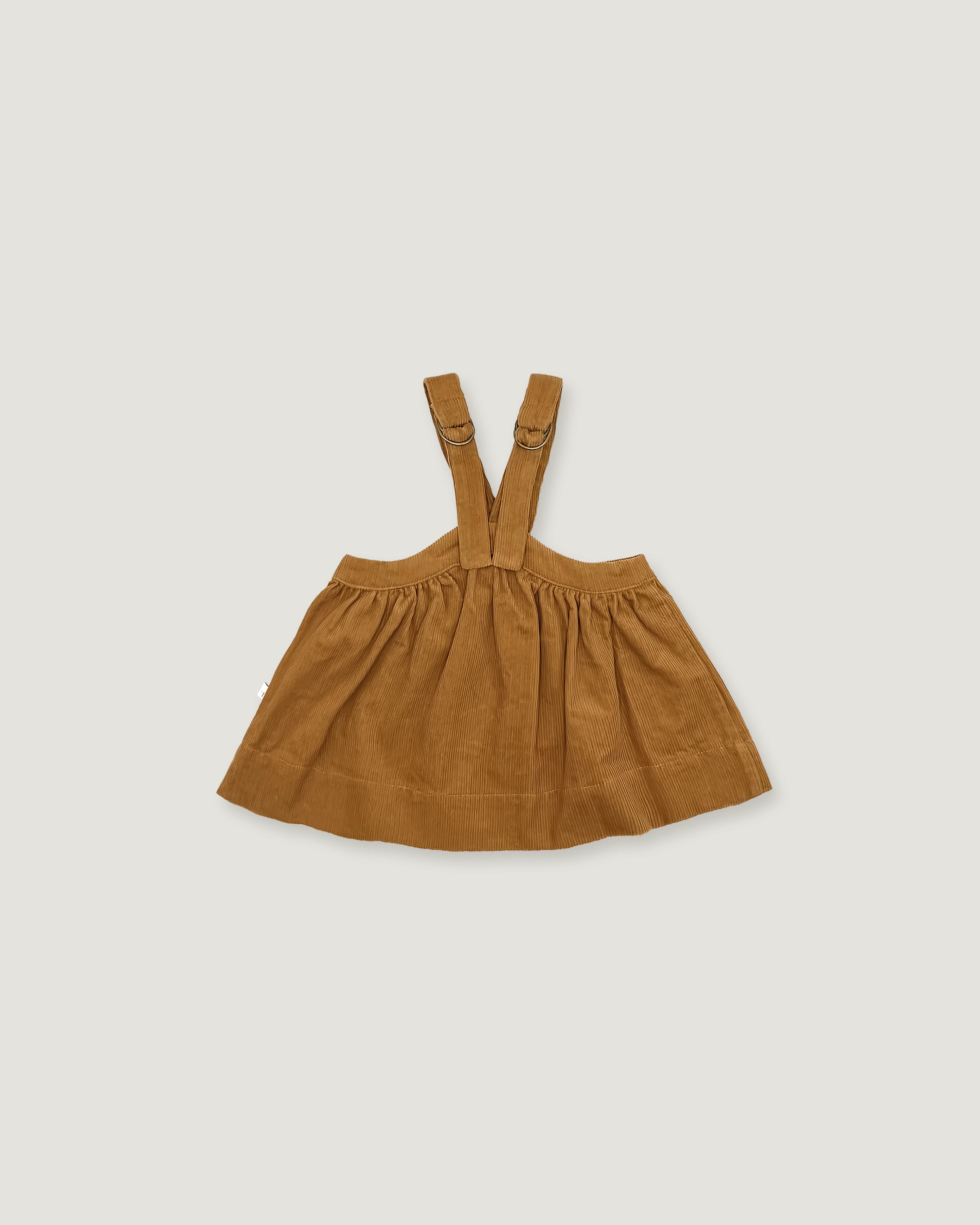 A toddler girl's brown corduroy pinafore dress with adjustable shoulder straps, laid flat on a light gray background.