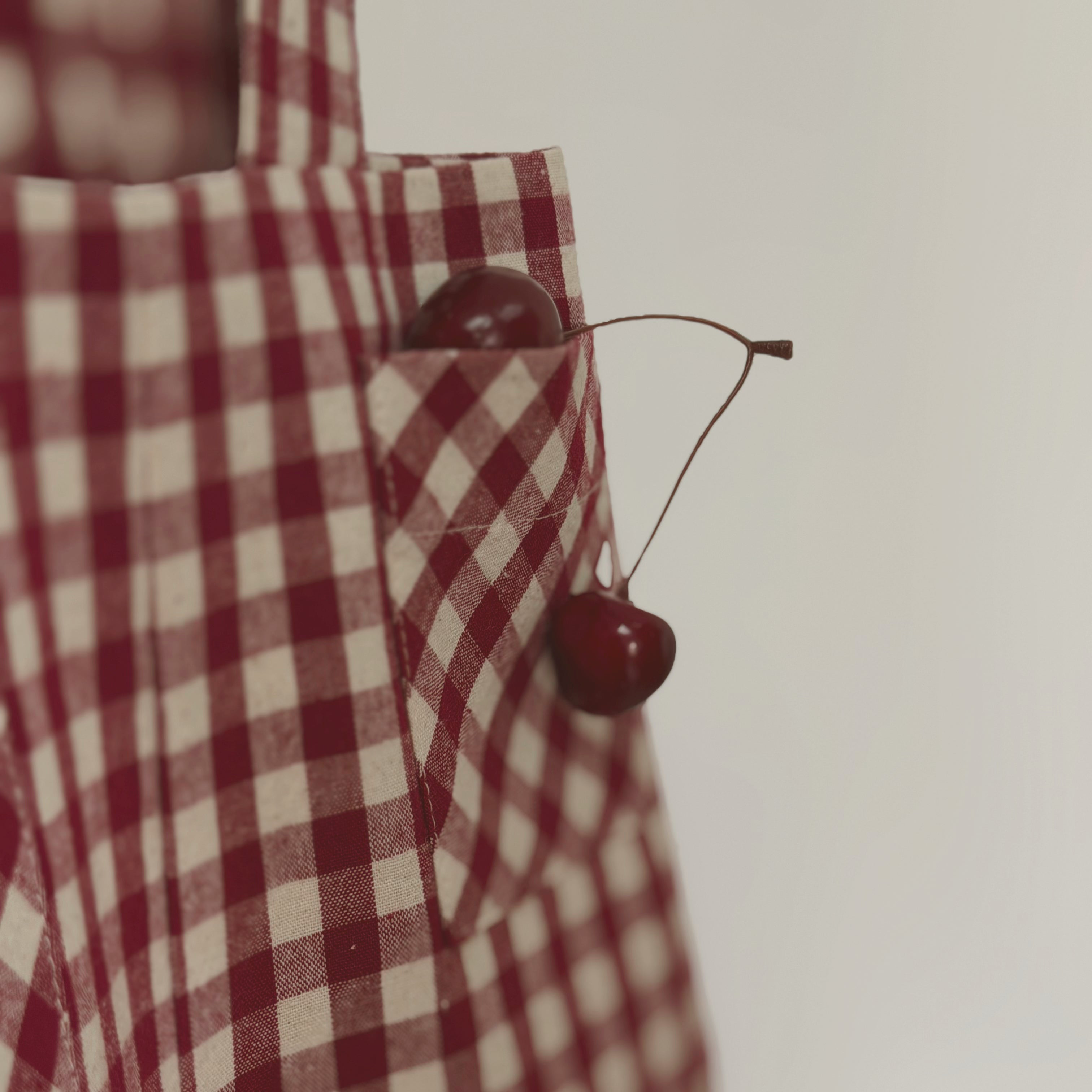 Red and white checkered dress with a cherry detail on a plain background