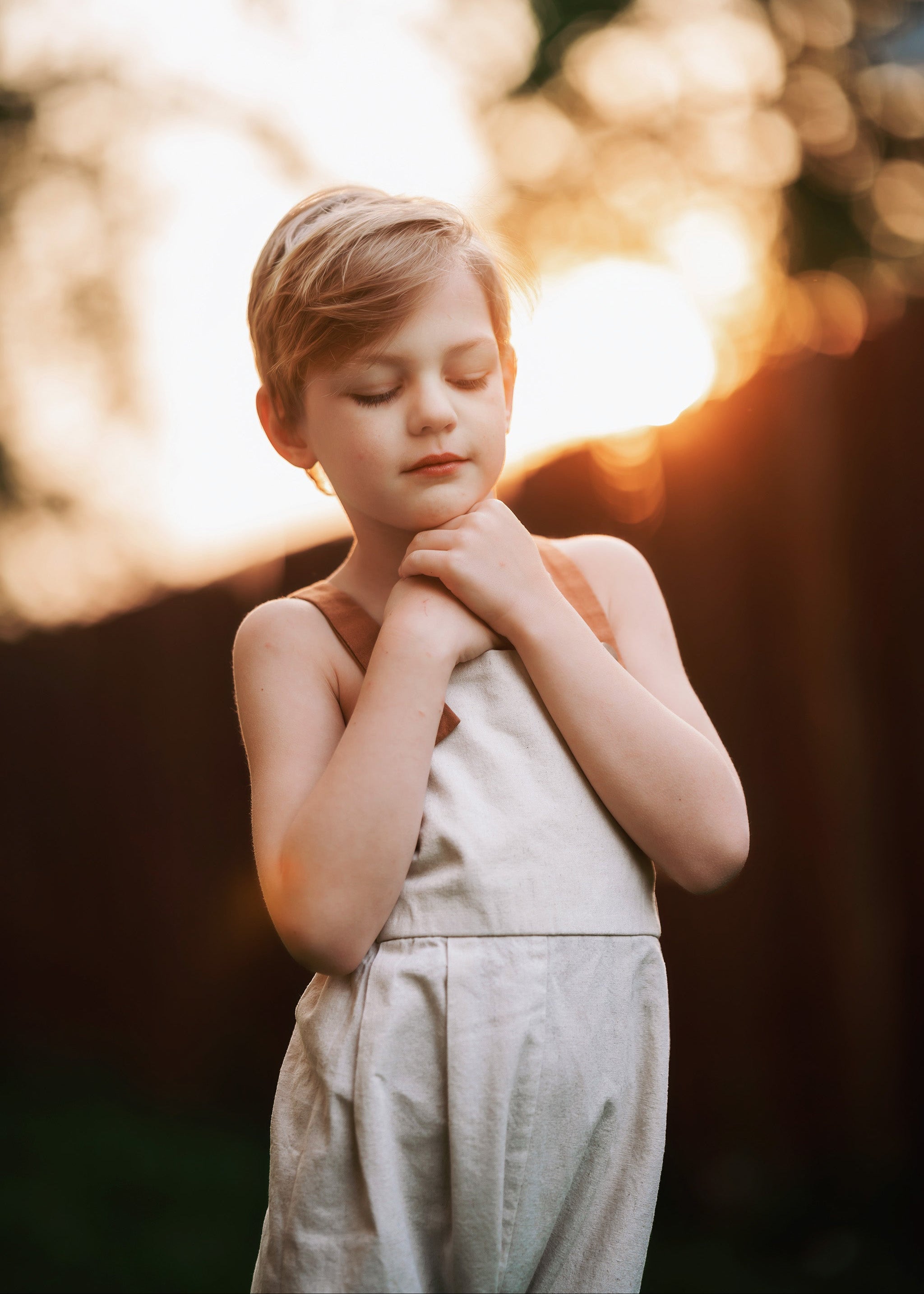 Child in natural linen overalls with a blurred natural background