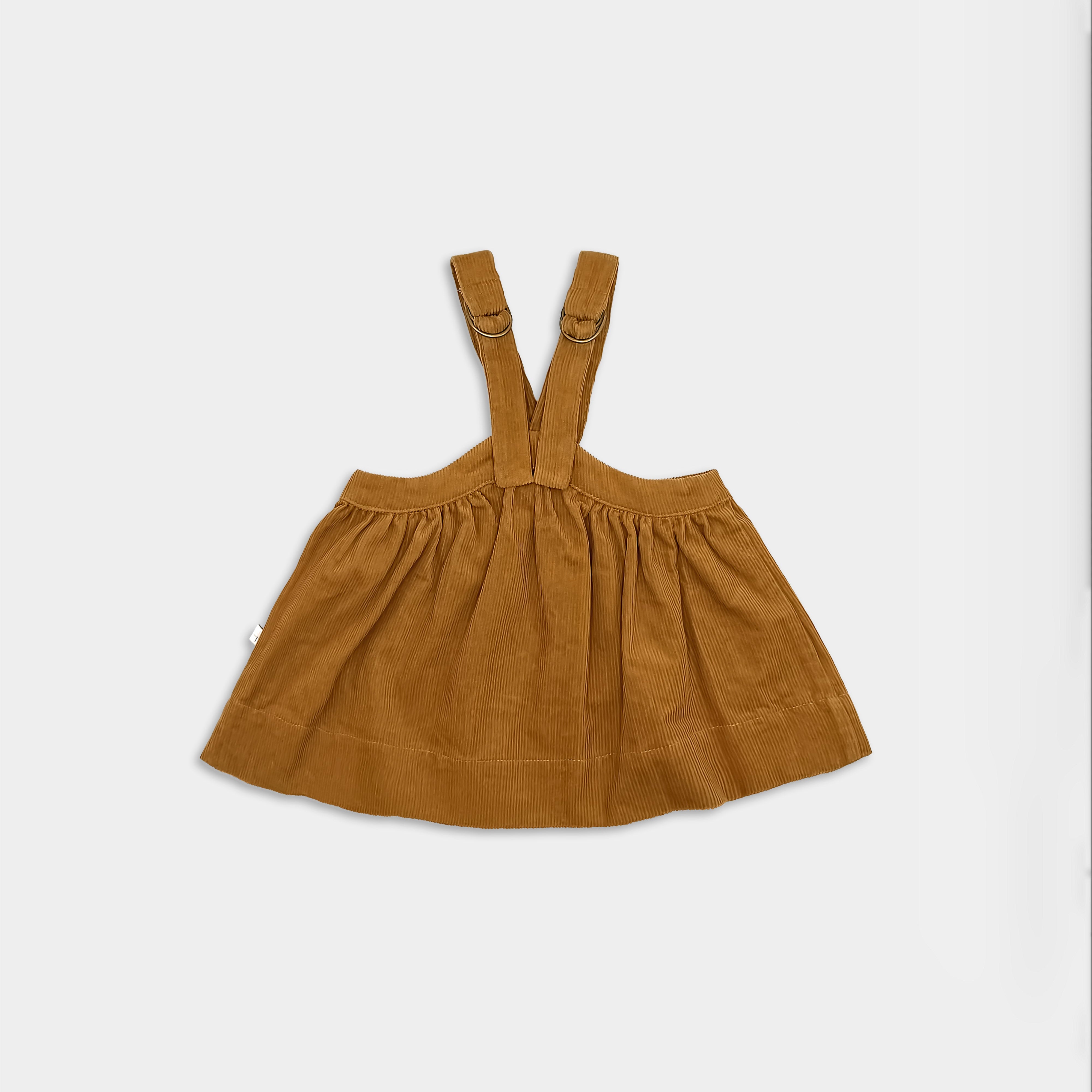 Back view of mustard corduroy dress with suspenders on a light grey background