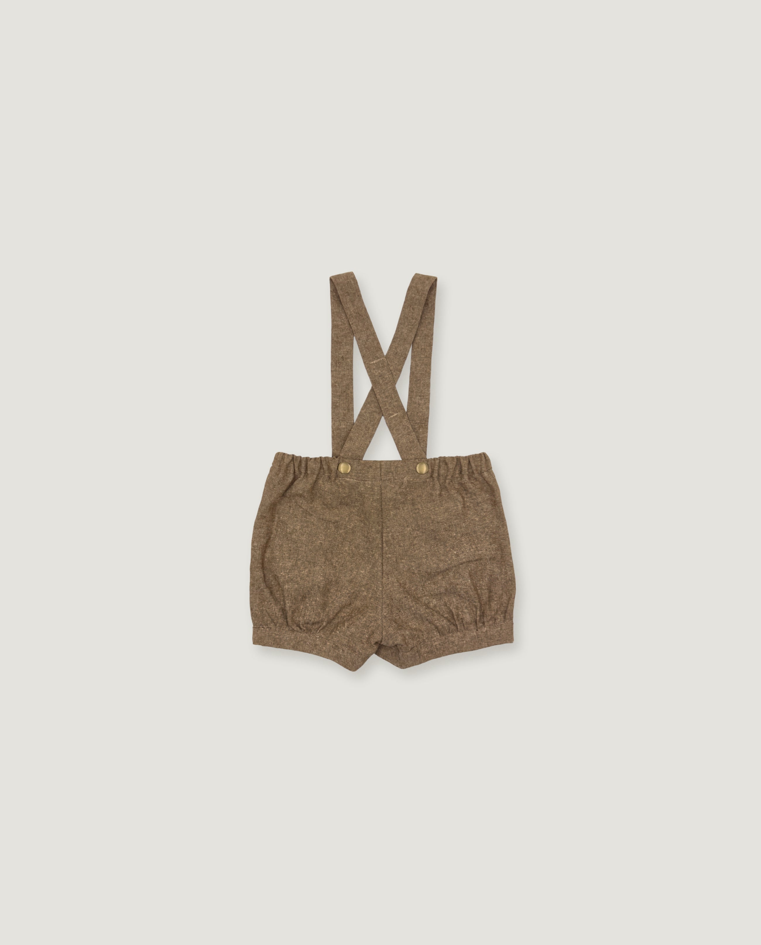 A pair of toddler's brown suspender shorts with a textured woven fabric, laid flat on a light gray background.