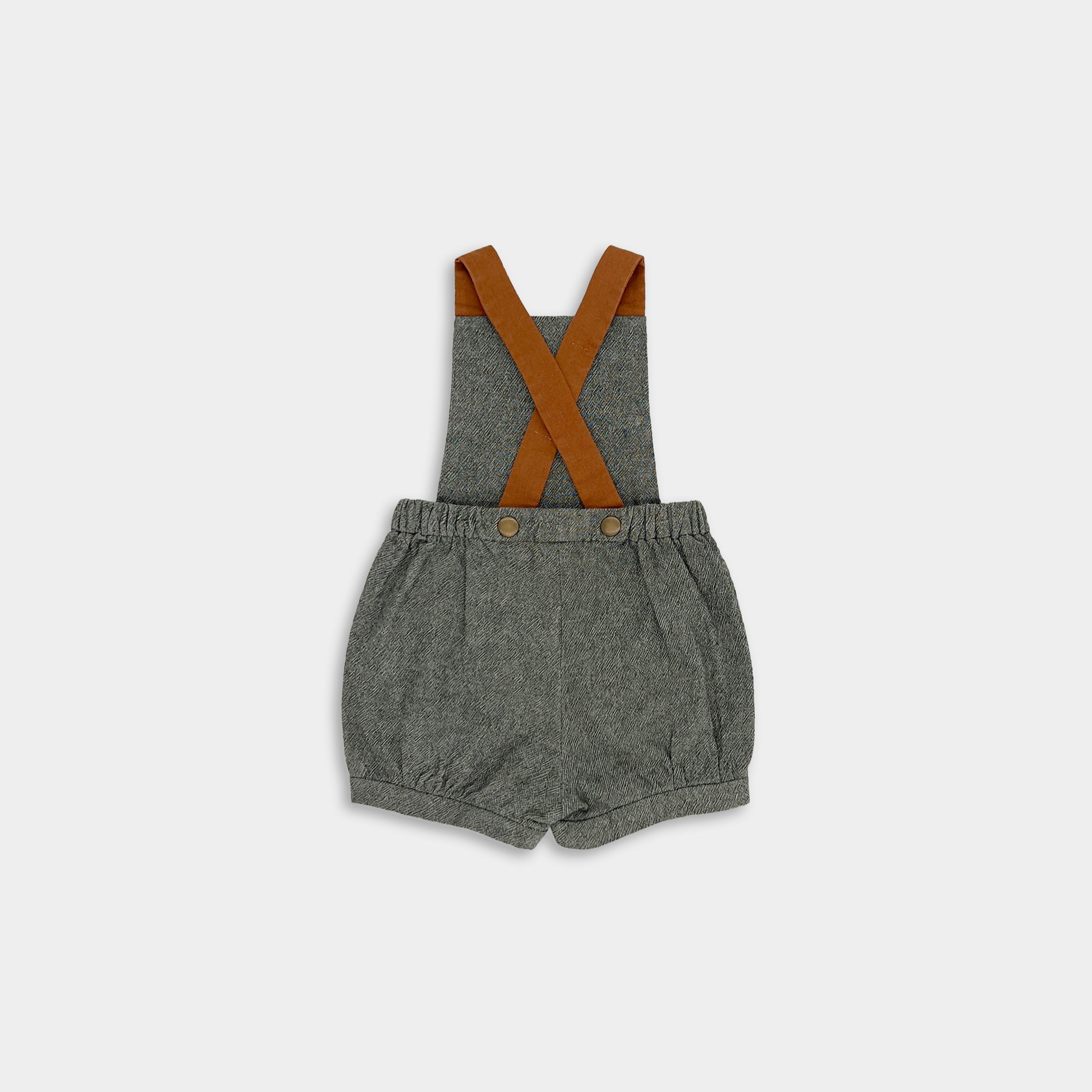 Green romper with brown suspenders on a white background