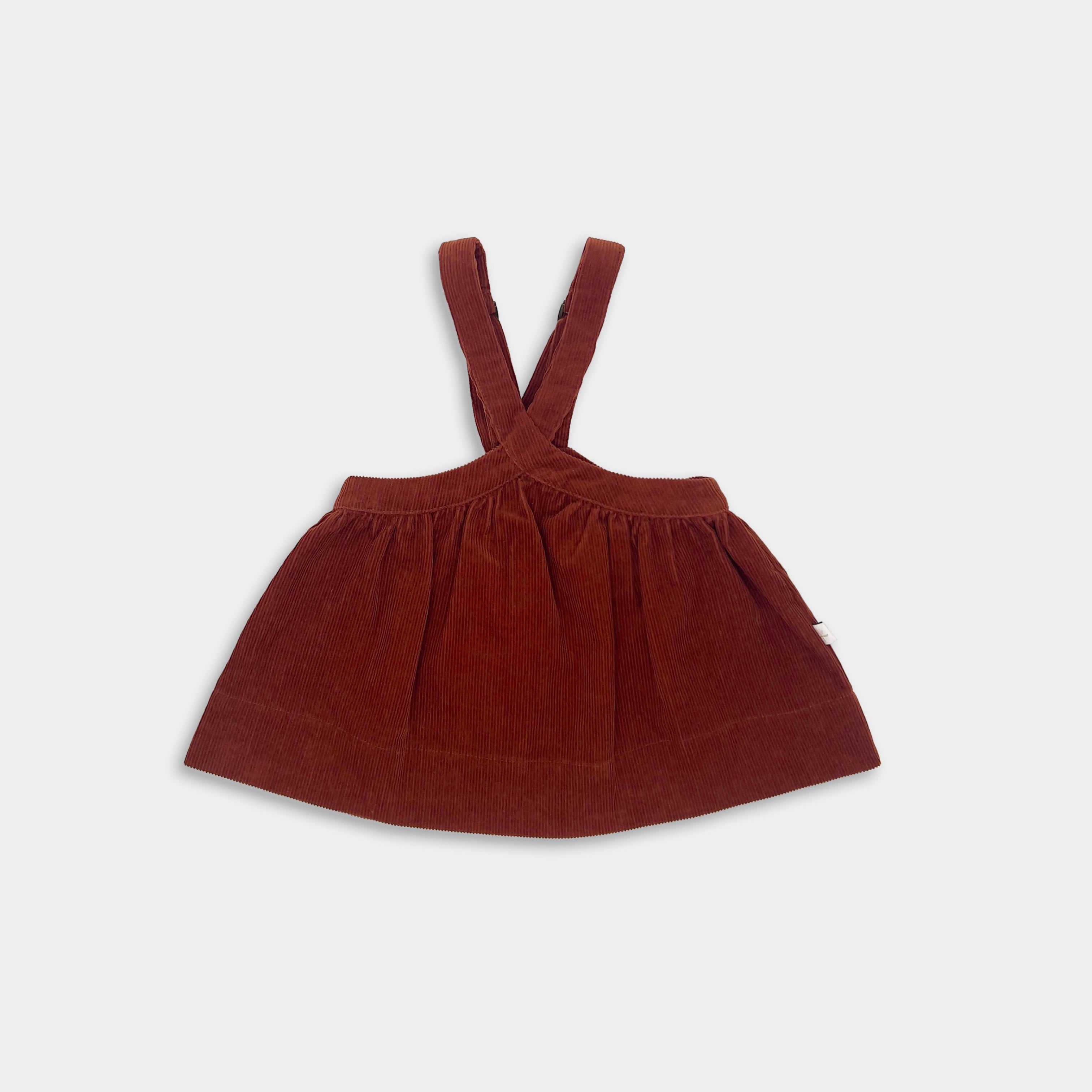 Brown red corduroy dress with suspenders on a white background