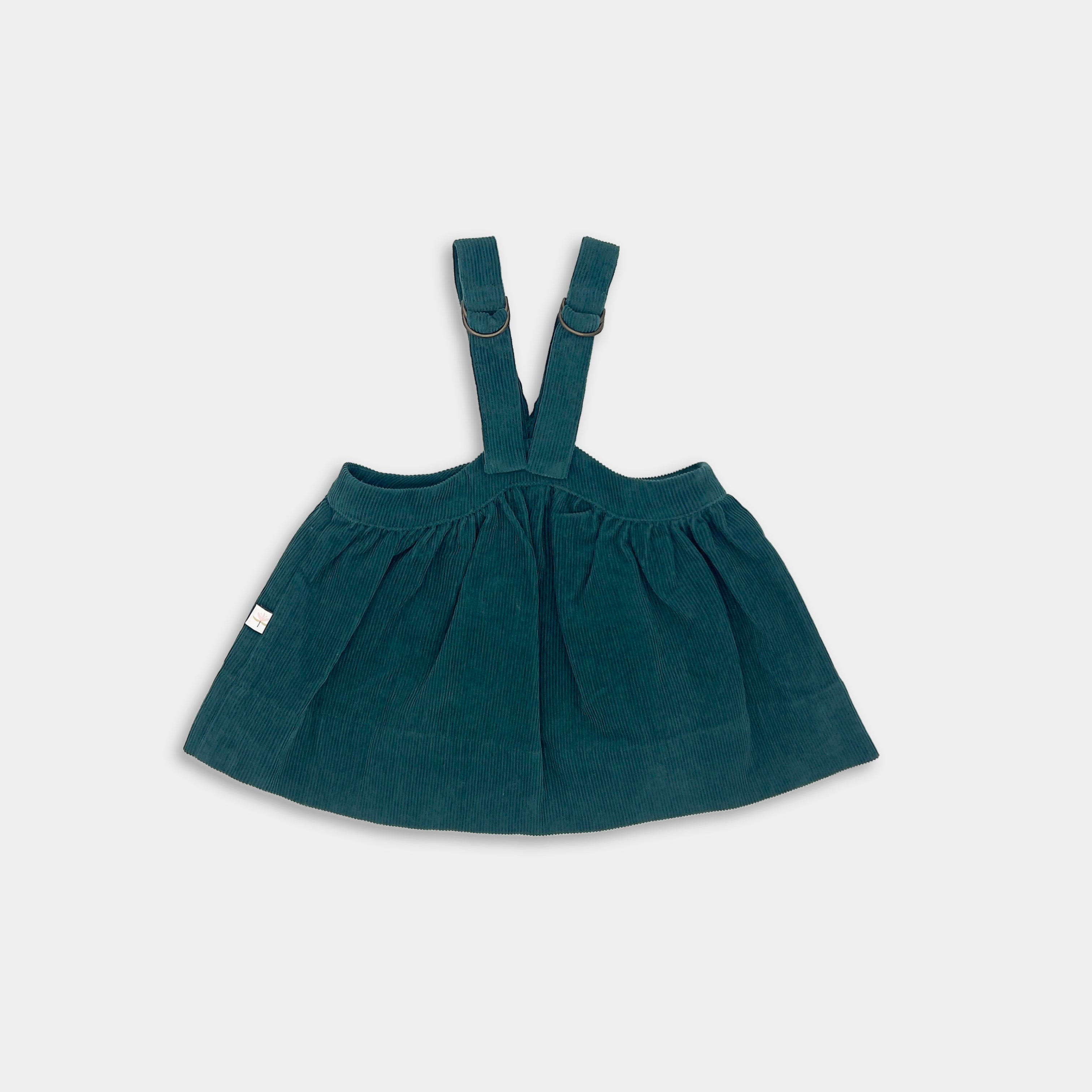Green children's dress with suspenders on a white background