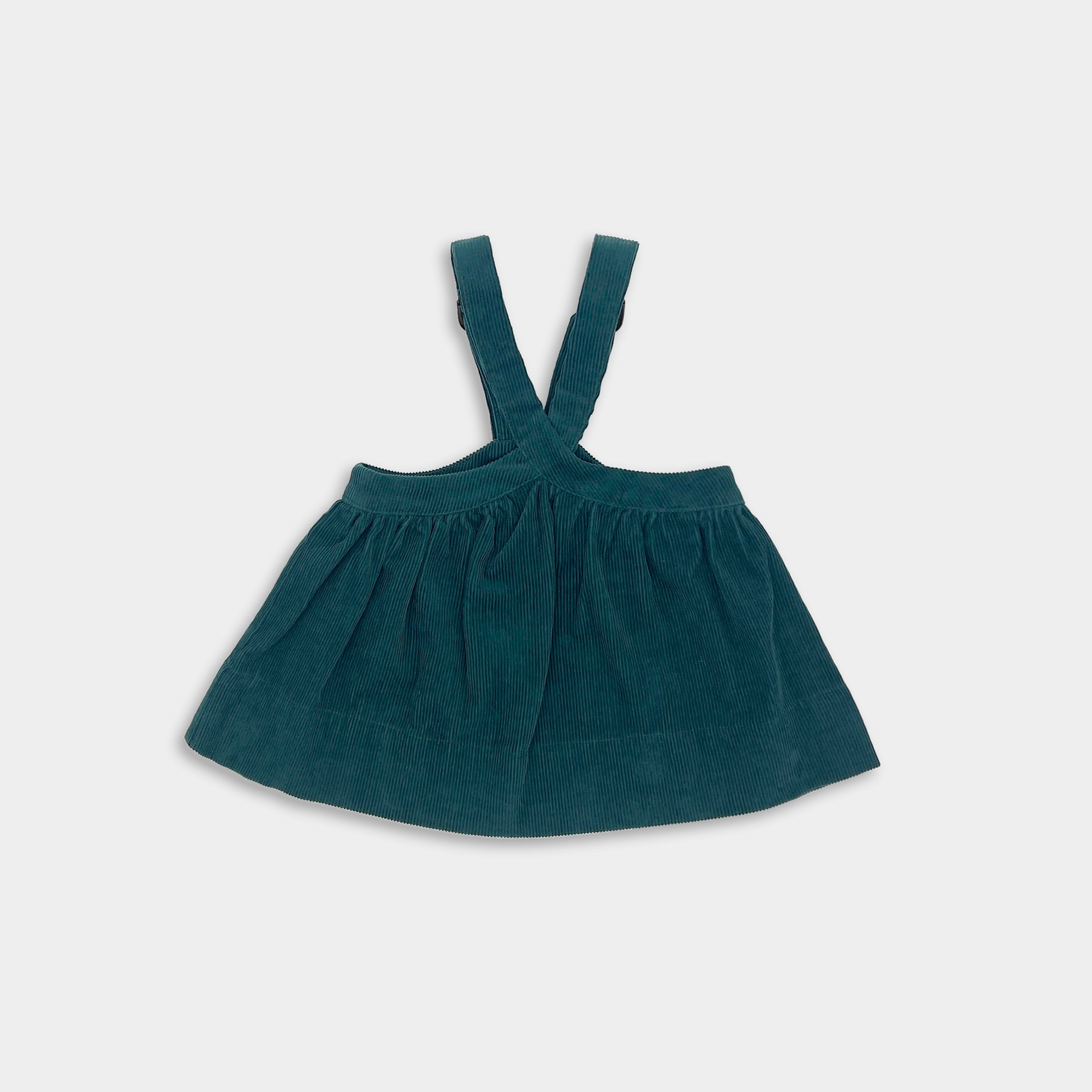 Green dress with suspenders on a light gray background