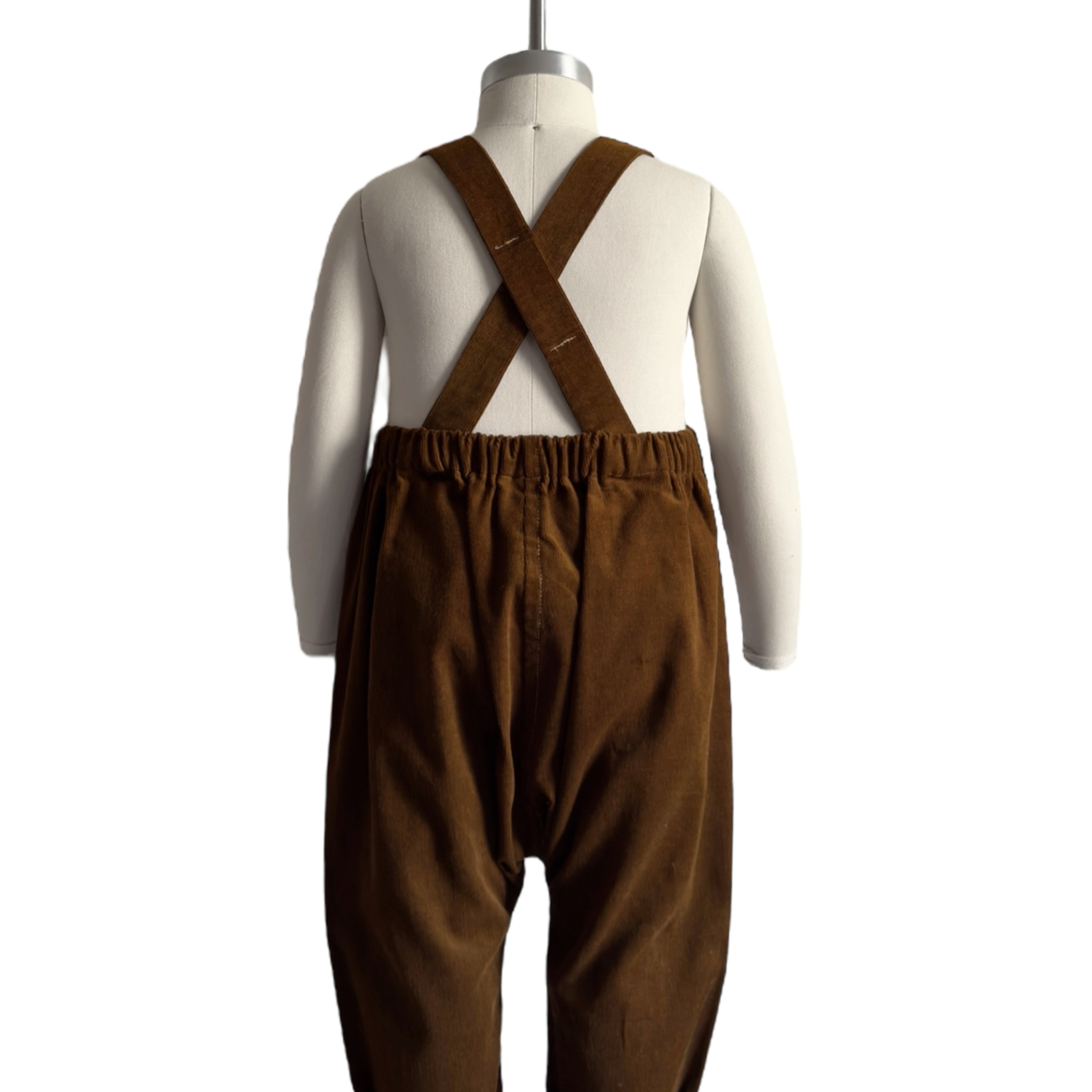 Back view of handmade cocoa brown long overalls displayed on a mannequin, showcasing the adjustable straps and unfoldable leg cuffs, highlighting the thoughtful design for comfort and longevity.