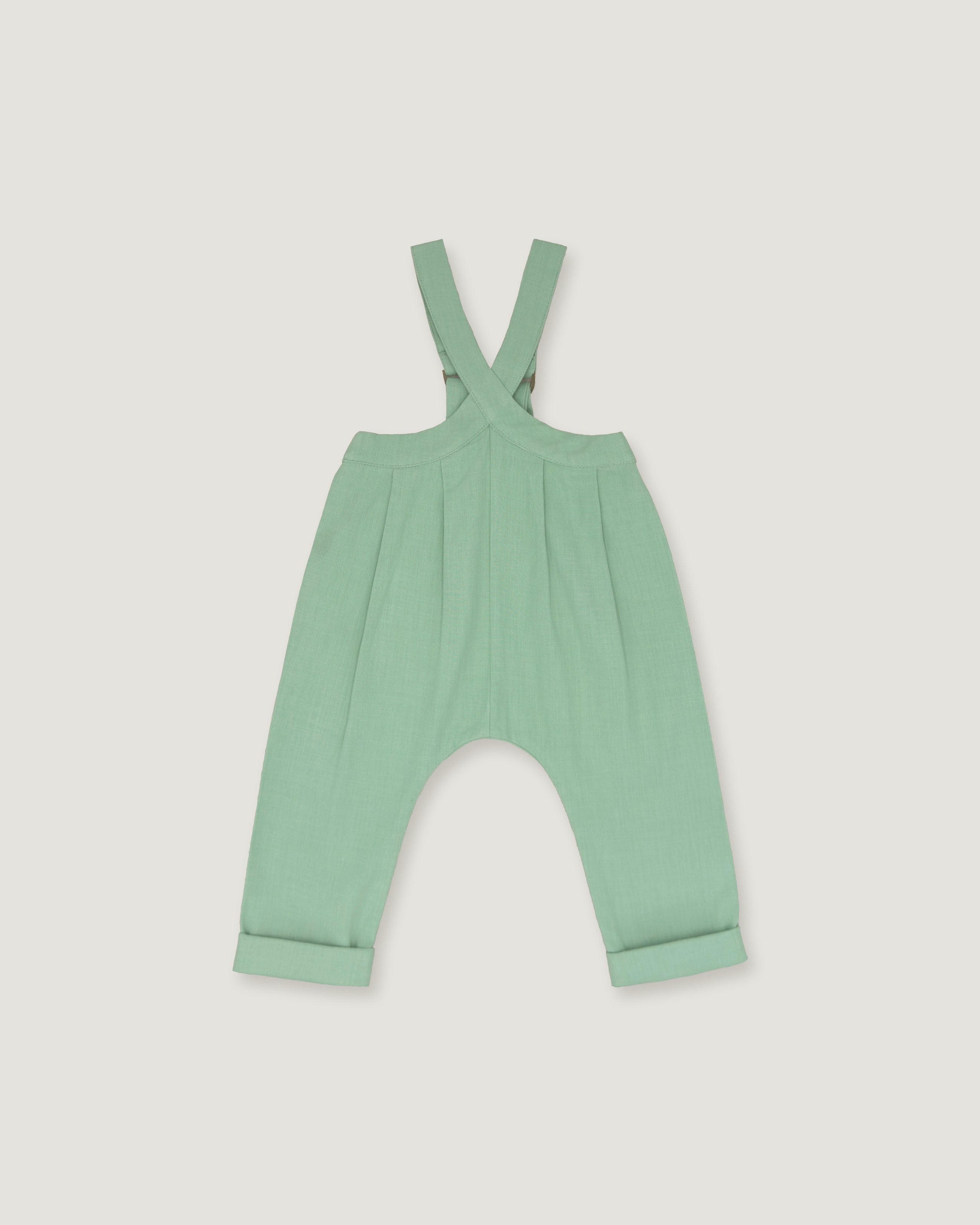 A mint green baby romper with adjustable shoulder straps and a wide leg design, shown flat on a light gray background.
