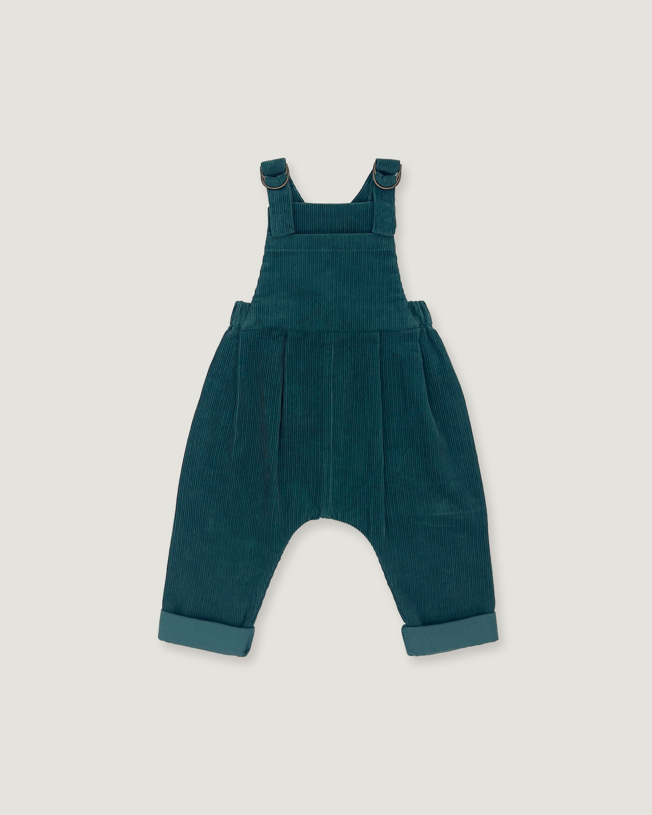 A pair of toddler corduroy overall jumpsuit in a deep teal blue-green color, featuring adjustable shoulder straps that cross over the chest and cuffed harem-style legs, shown flat on a light gray background.