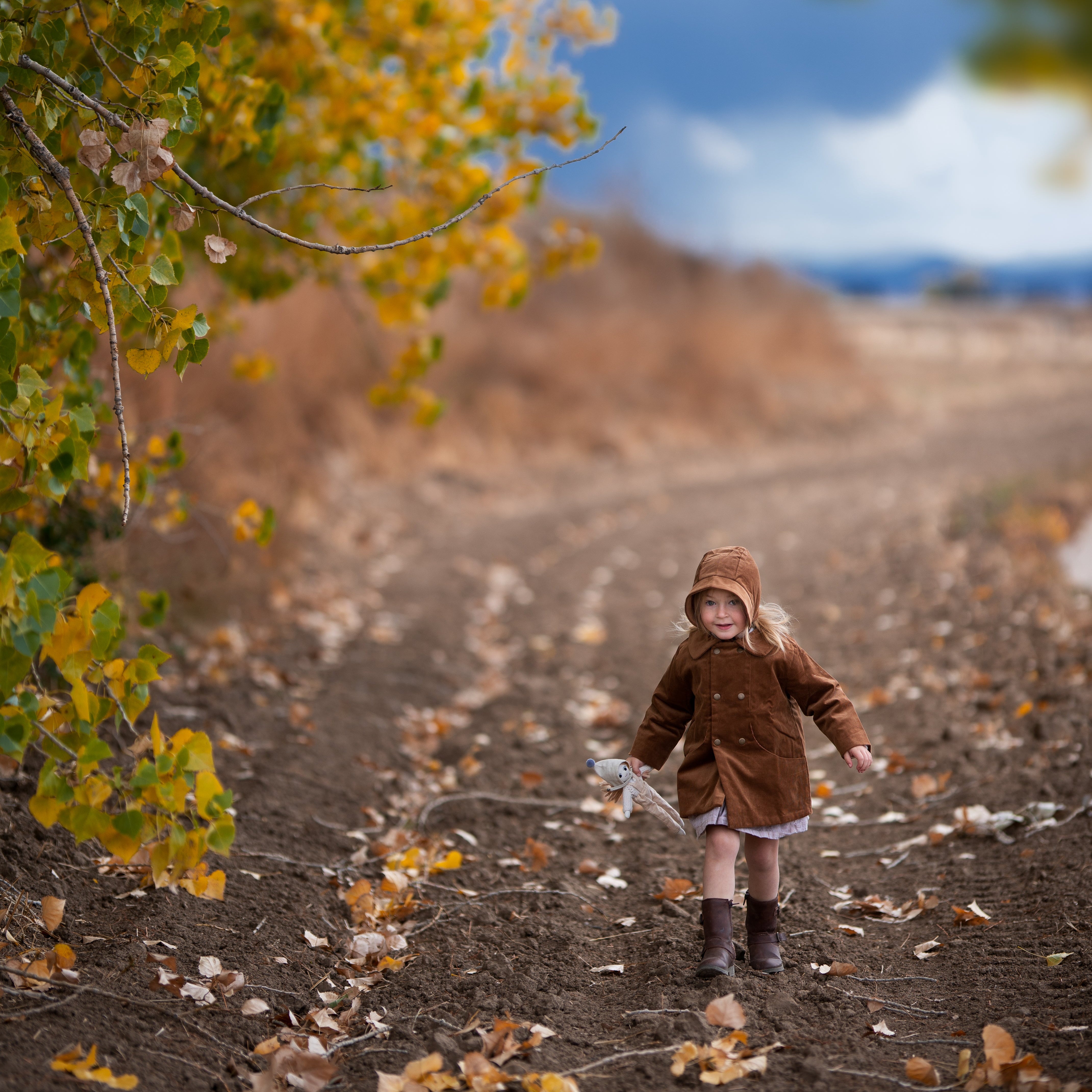 Model girl wearing the Camel Bonnet, in action - Capturing the model engaged in playful activity, this image emphasizes the bonnet’s functionality and stylish appeal as it keeps her warm.