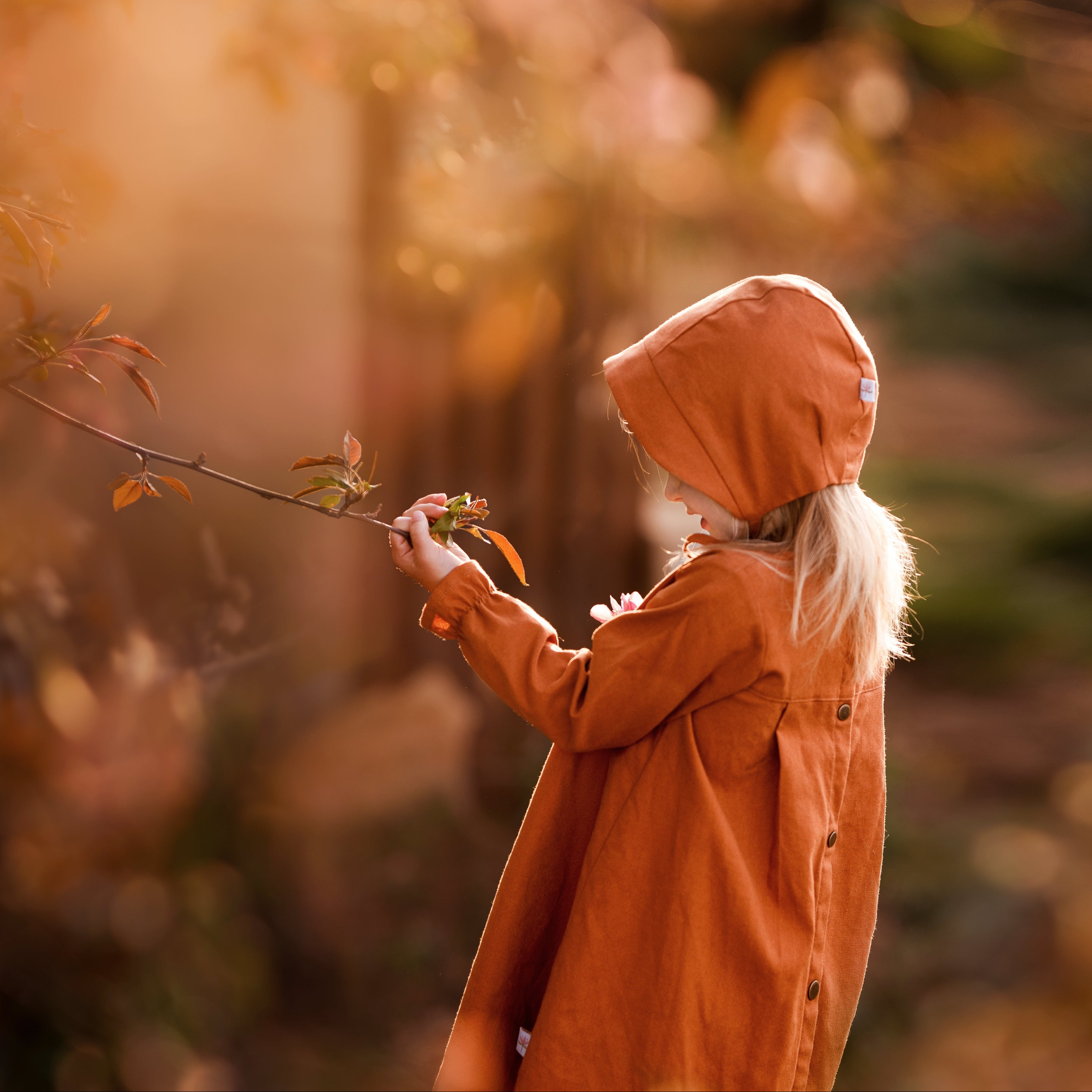 Girl in matching rust dress and bonnet looking at plants