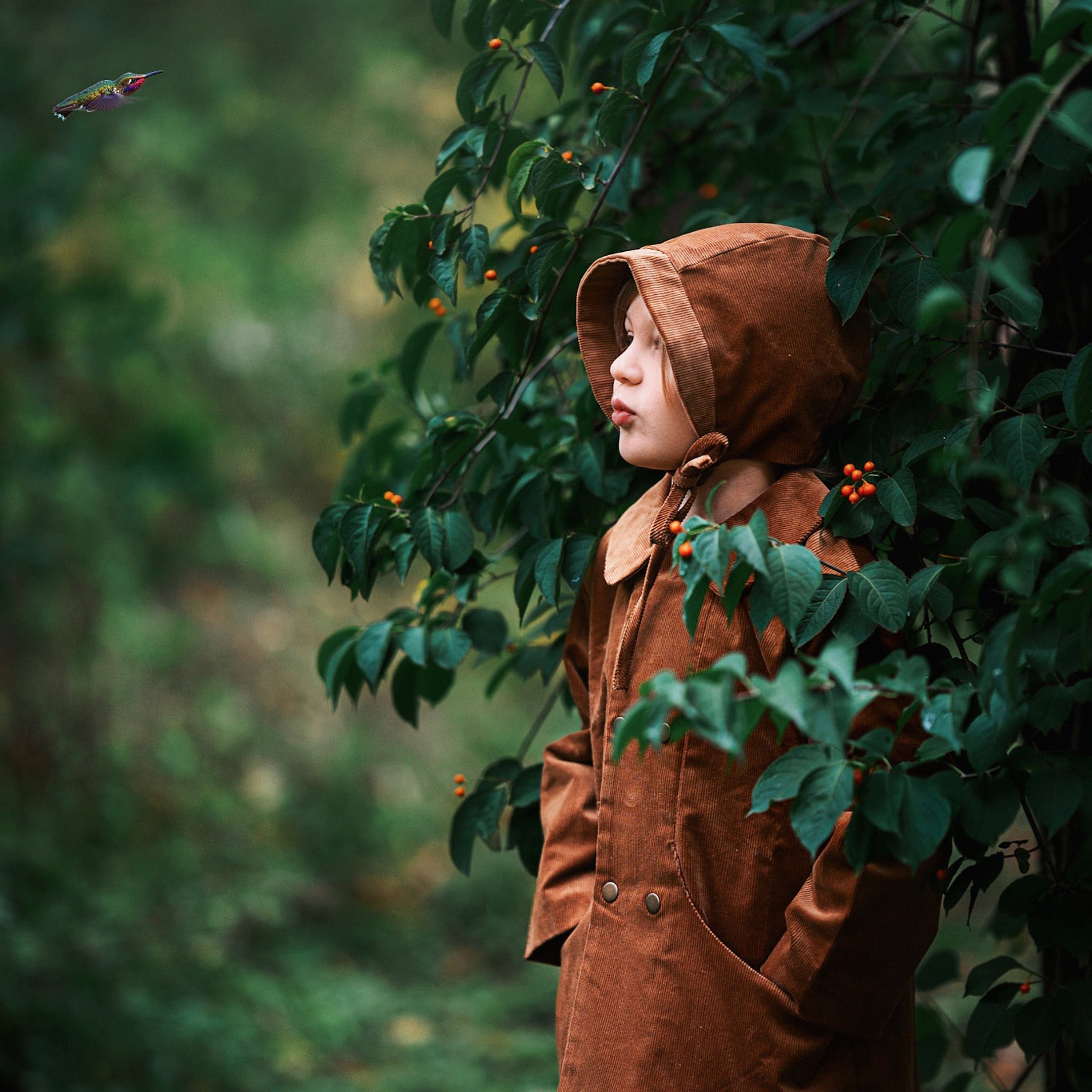 A detailed side view showcases Ezra wearing both the Camel coat and matching bonnet, highlighting the sustainable design that kids will love.