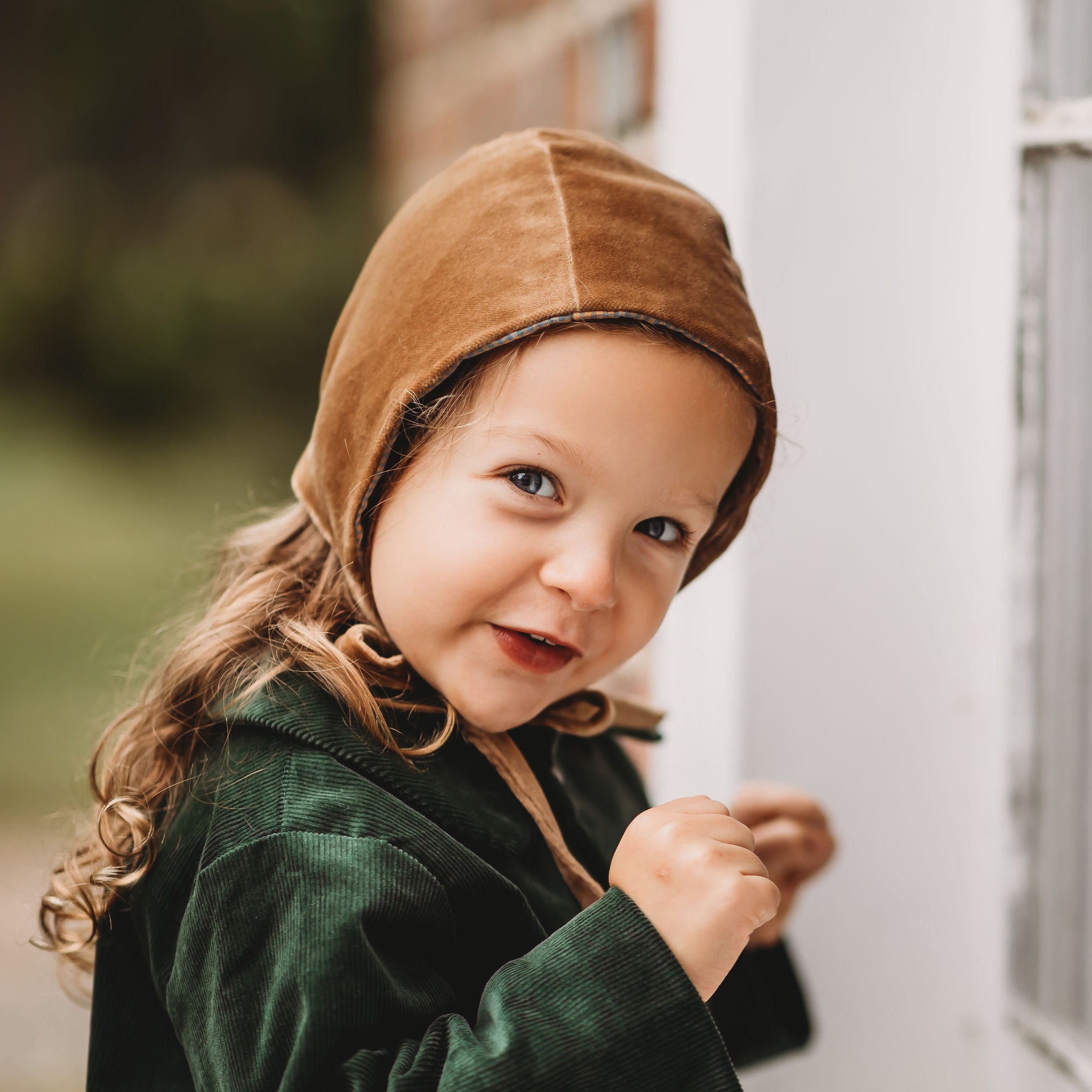 Adorable 3-year-old girl wearing the Gold Velvet Bonnet, capturing the essence of childhood joy and the elegant design of this luxurious accessory.