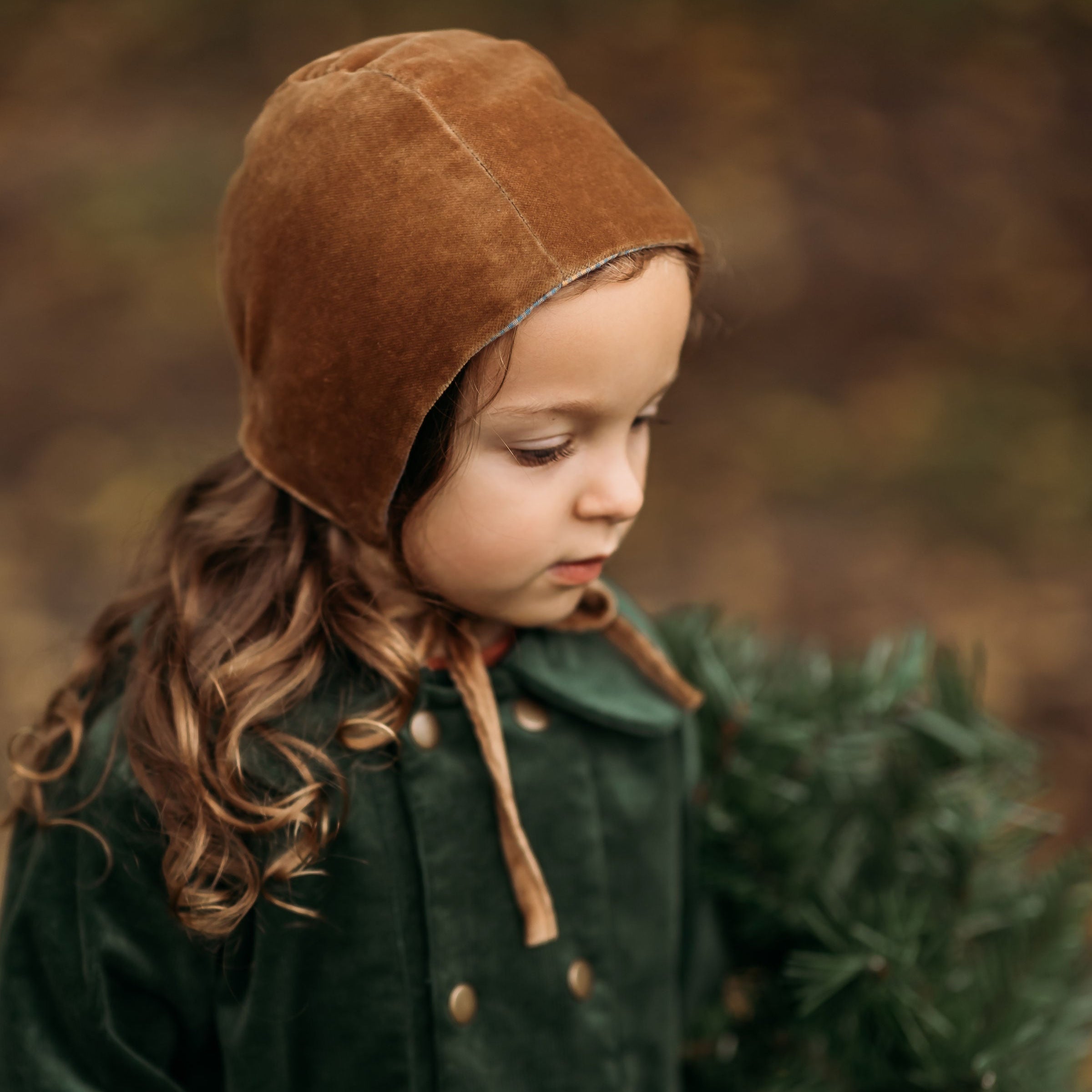 Side view of the Gold Velvet Bonnet on a model, emphasizing the soft brushed gingham cotton interior that provides gentle comfort against delicate skin.