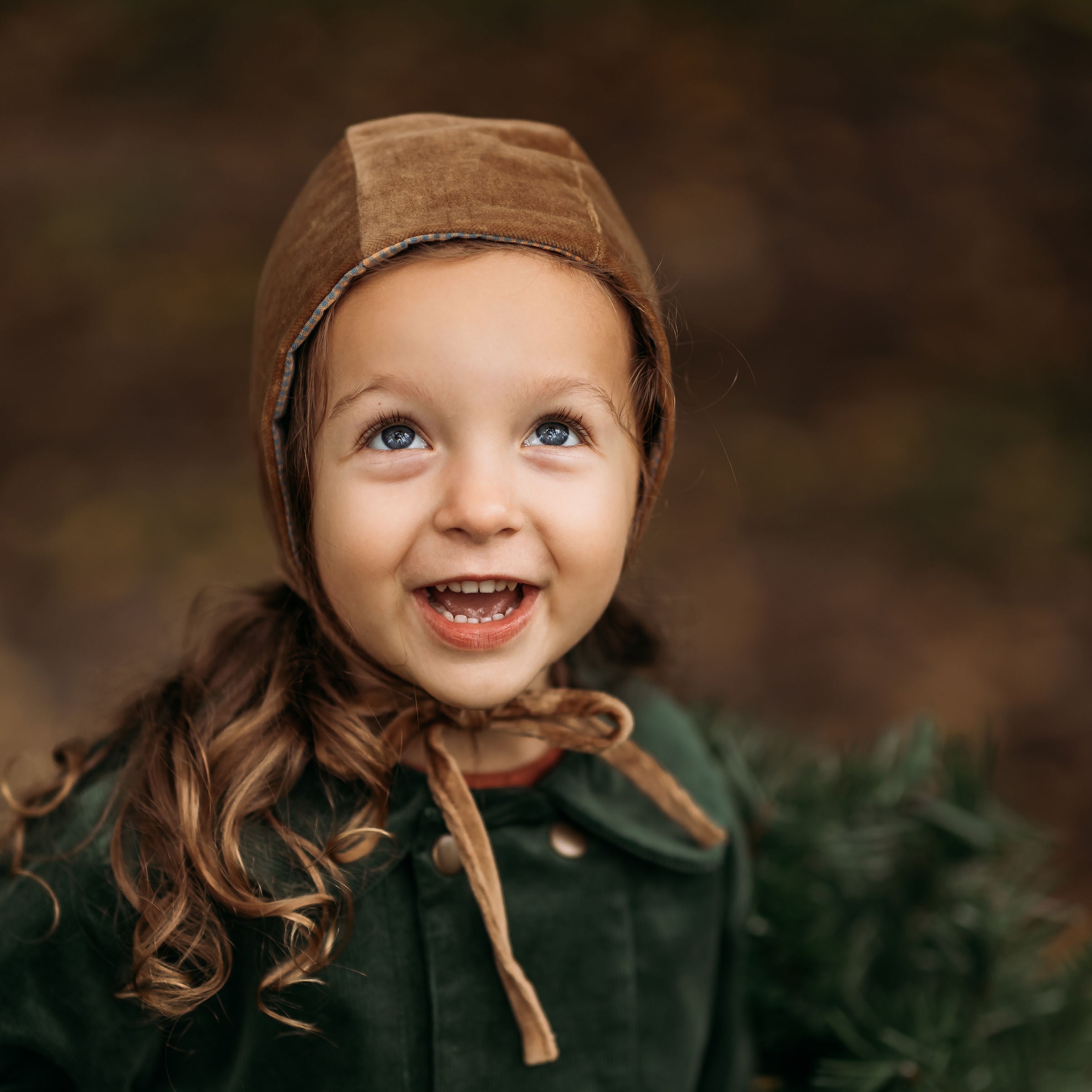 3-year-old girl happily wearing the Gold Velvet Bonnet, highlighting its sophisticated style and rich velvet fabric that enhances any outfit for formal events or everyday wear.