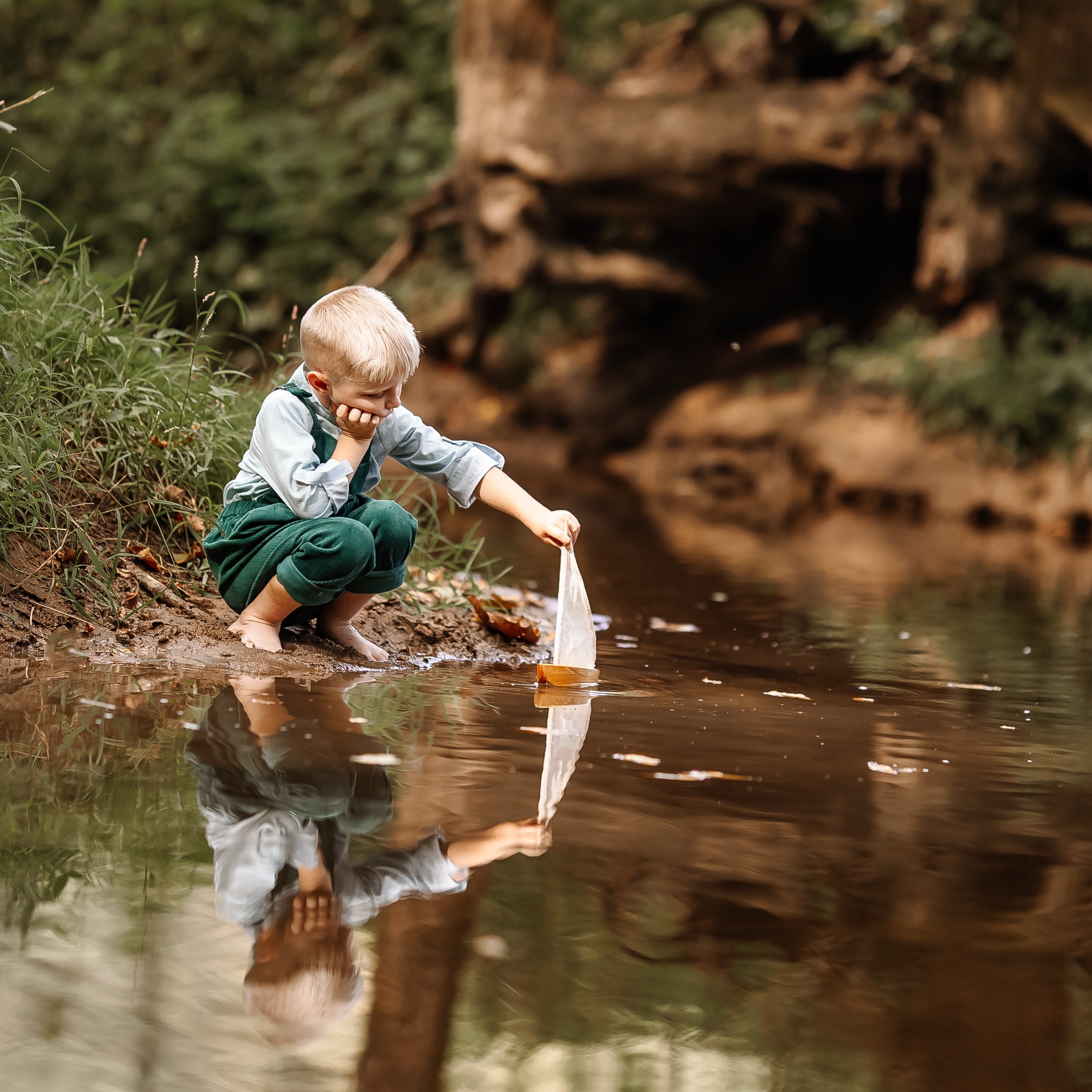 Child playing by a stream with reflection in the water