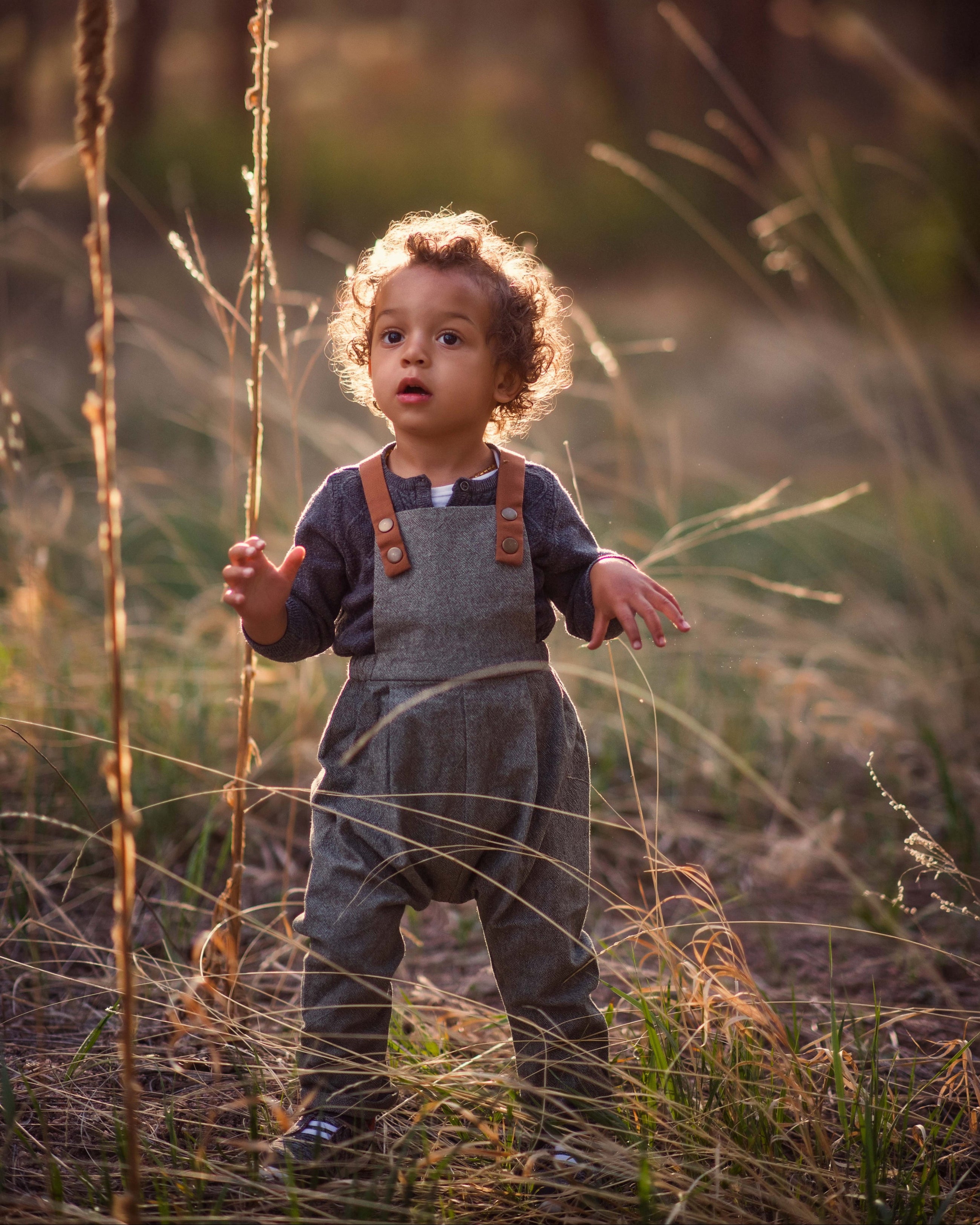 Child standing in tall grass with a blurred natural background