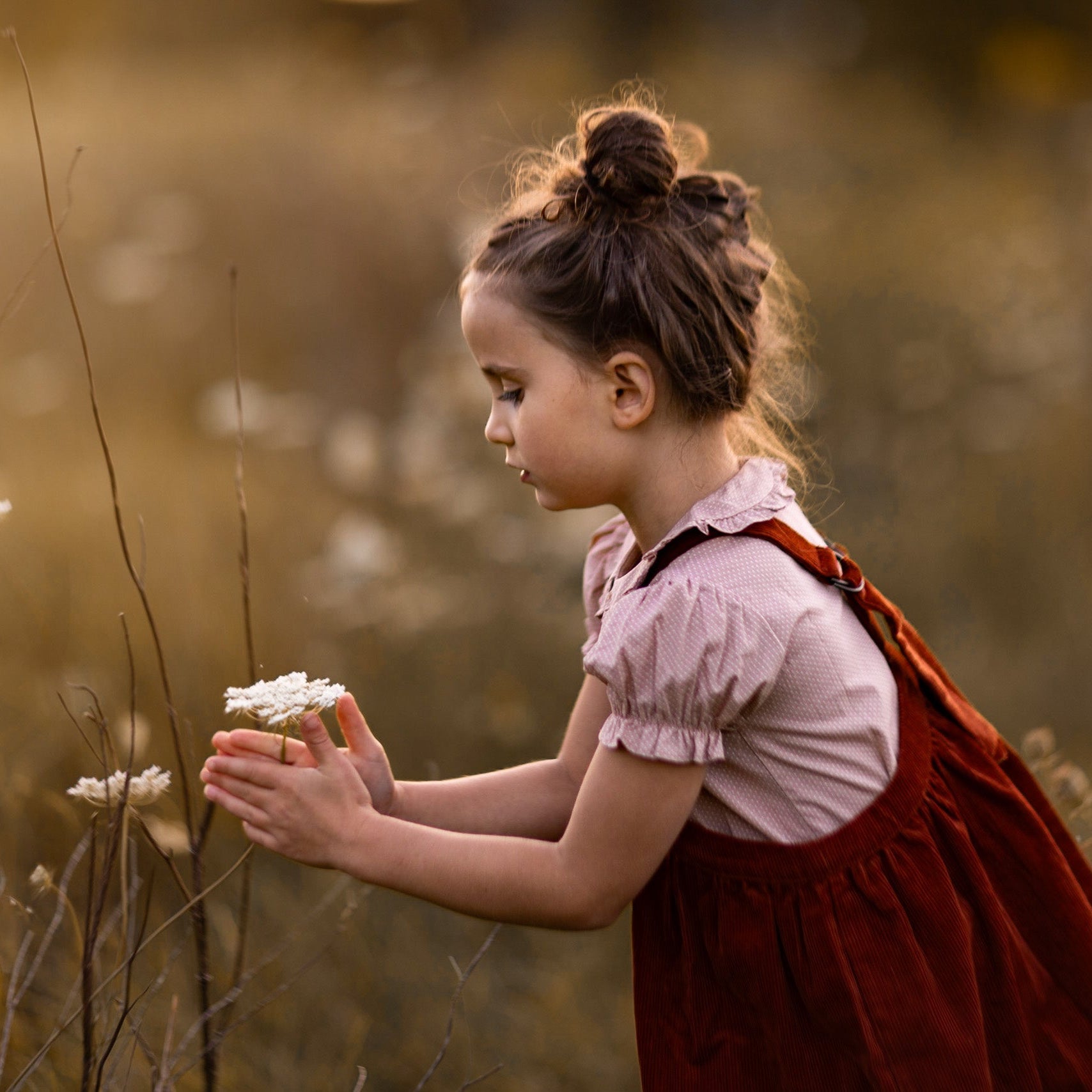 Young girl in a red dress holding flowers in a field